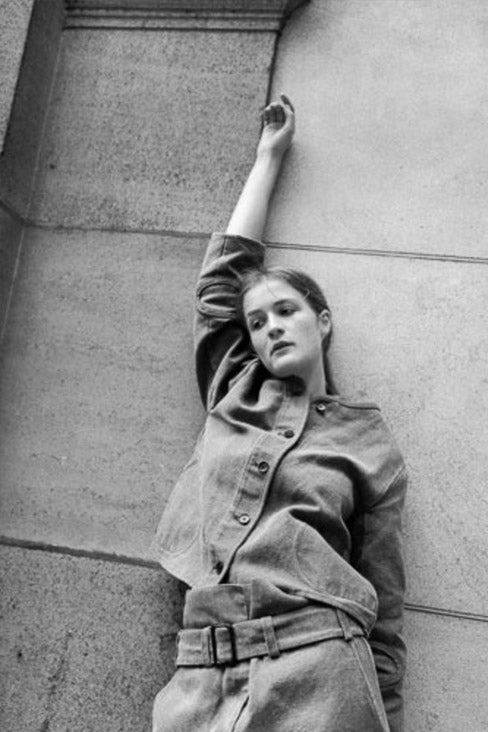 black and white photo of a woman arm reaching overhead and leaning on a granite wall wearing Tommy Jacket by Caron Callahan Dover Pant by Caron Callahan