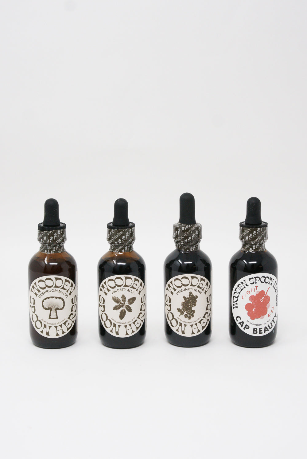 Four bottles of Wooden Spoon Herbs Anxiety Ally Tincture with varying labels displayed against a white background.