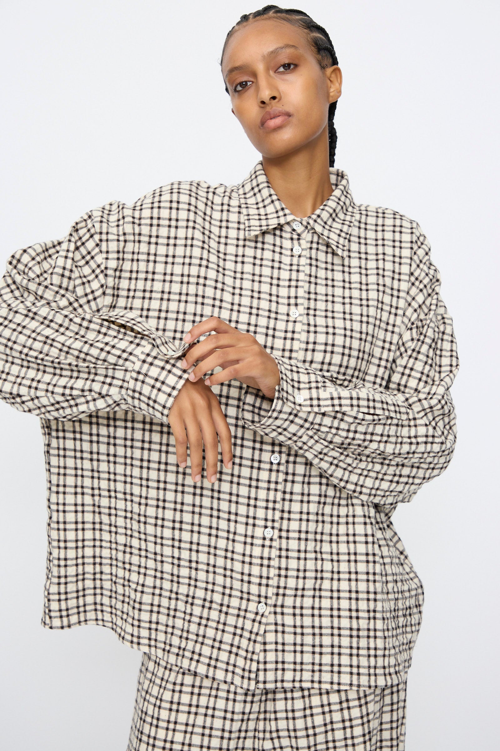 A person wears the AVN Over Shirt in White and Black Check, styled with matching pants, standing against a plain white background.
