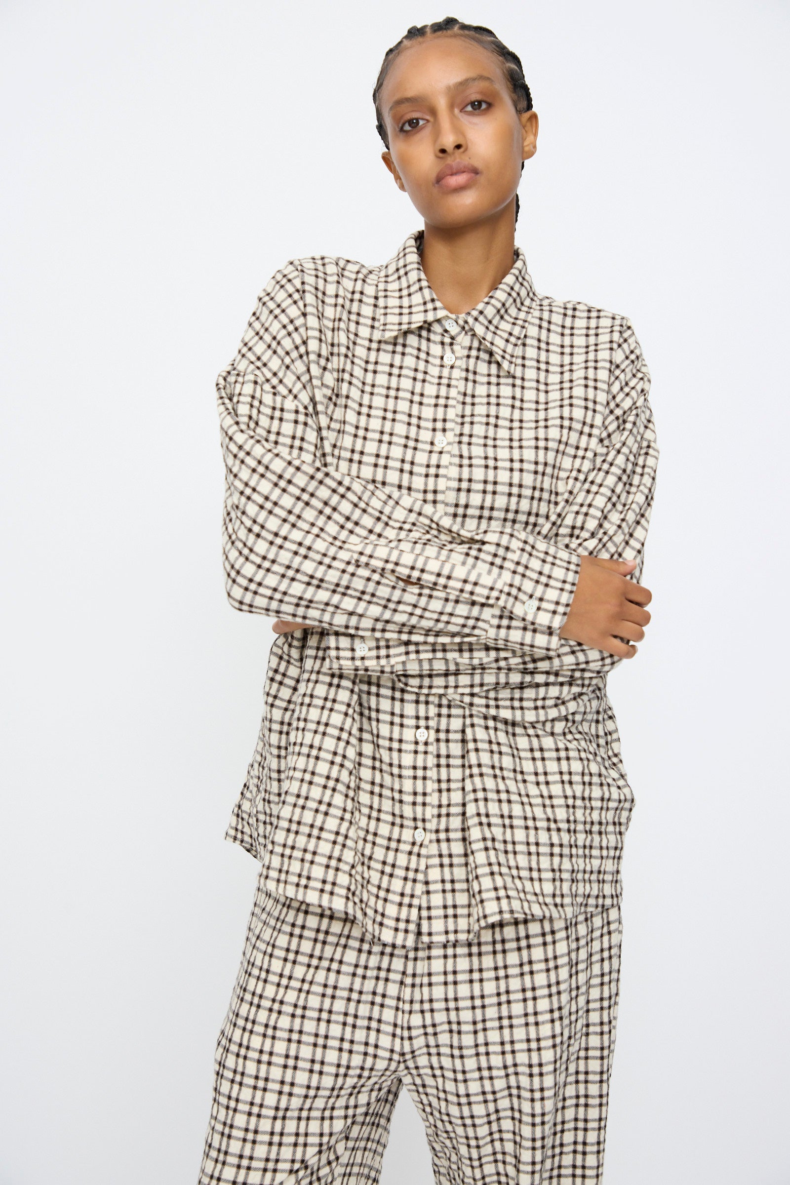 Person standing with arms crossed, wearing the AVN Over Shirt in White and Black Check, made in Italy, against a plain white background.