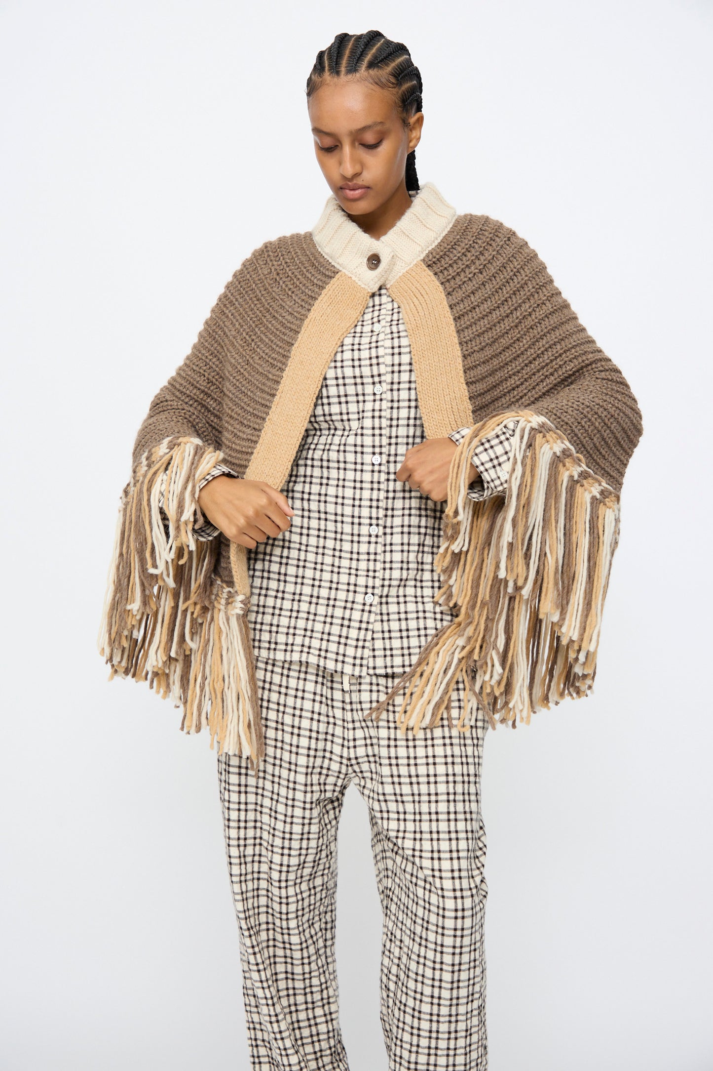 Model wearing AVN's Peru Poncho in Brown and Beige Placket, styled with a checkered outfit, stands against a plain white background.