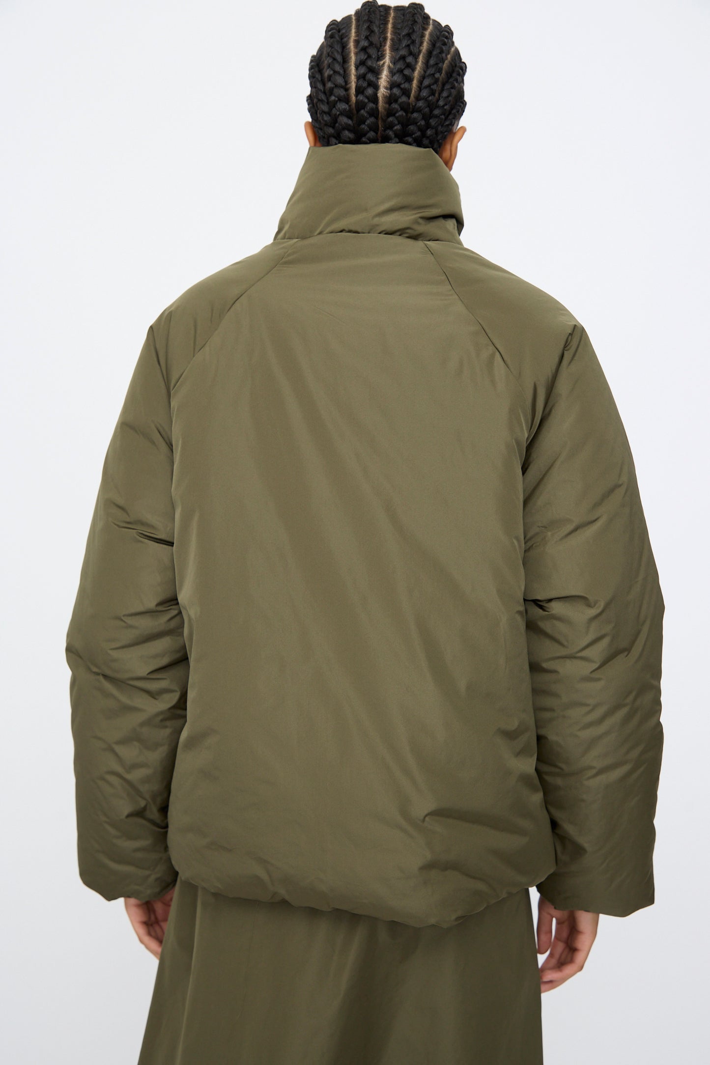 Person with braided hair wears an AVN Piumino Jacket in Military Green, oversized fit, seen from behind against a plain light background.