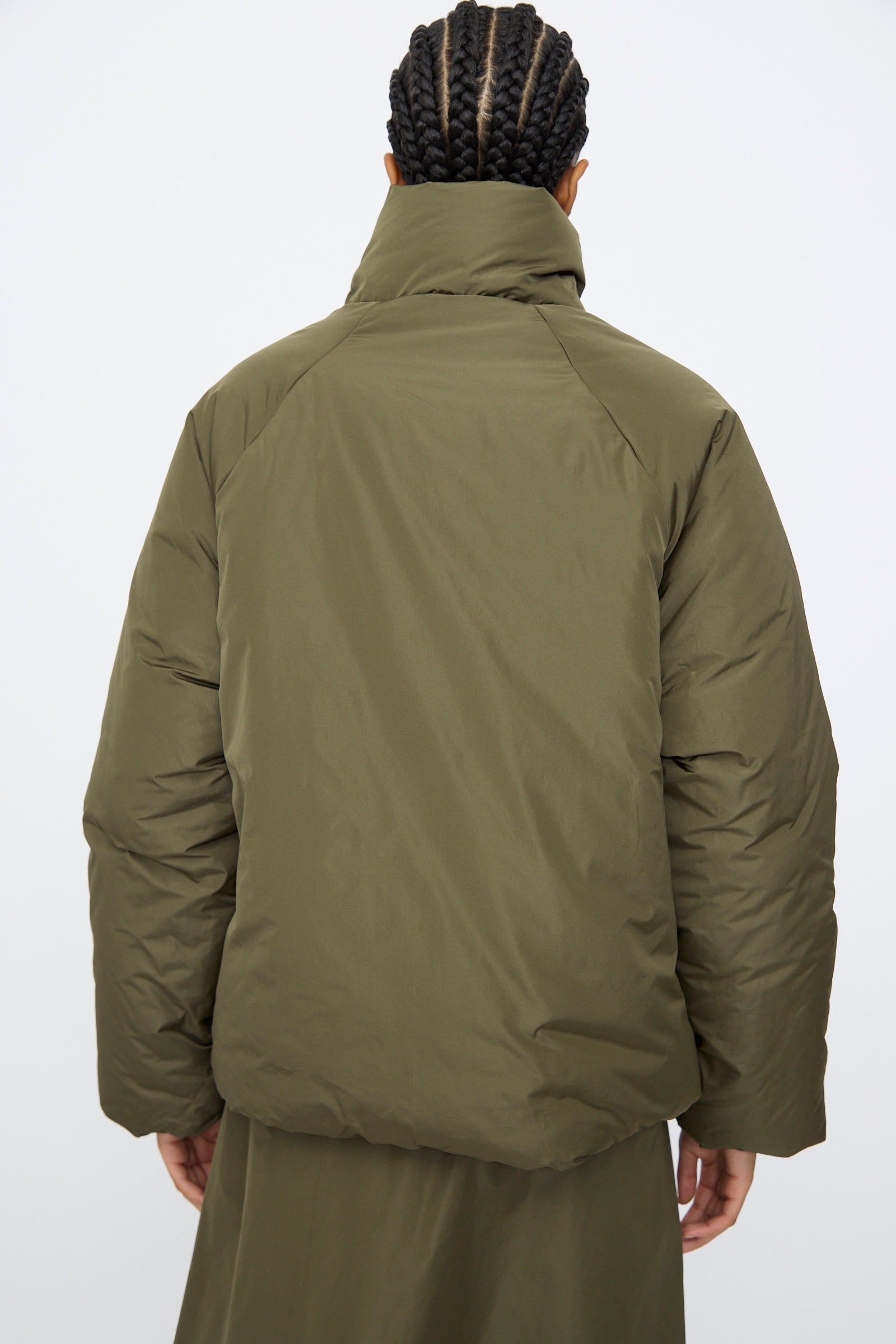 Person with braided hair wears an AVN Piumino Jacket in Military Green, oversized fit, seen from behind against a plain light background.