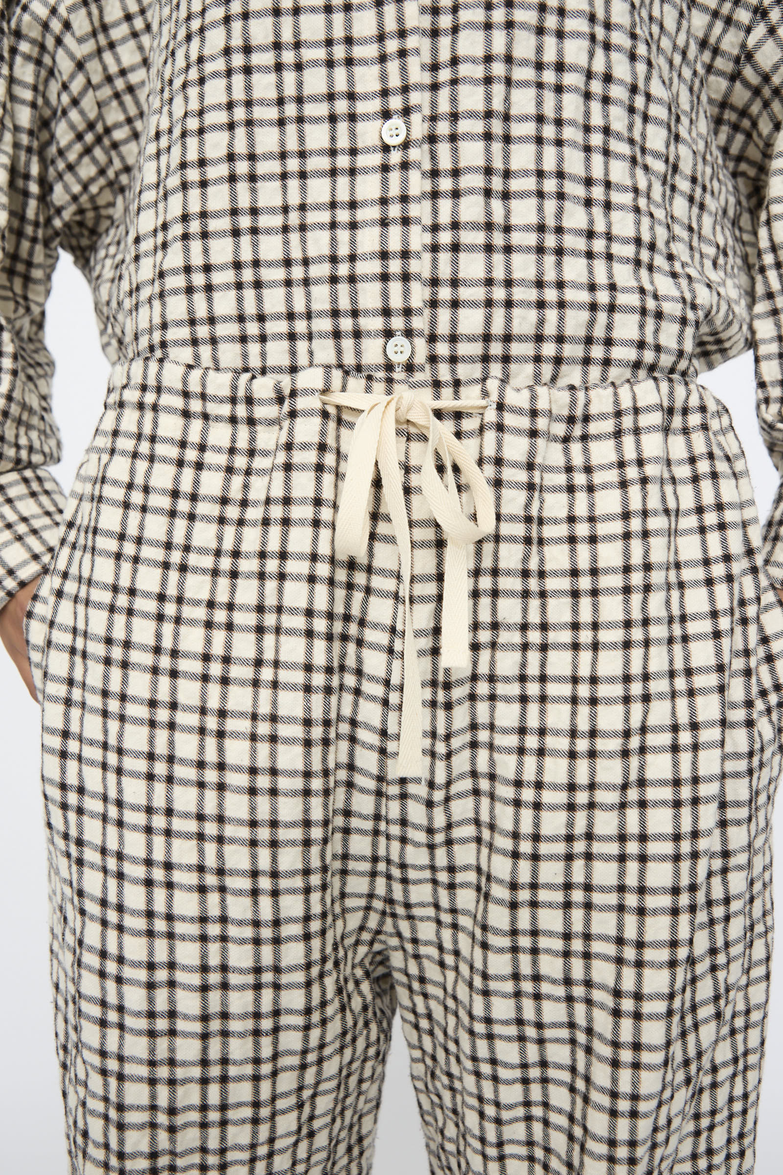 A person wearing AVN’s Pj Pants in White and Black Check, featuring a relaxed fit, drawstring waist, and side pockets.