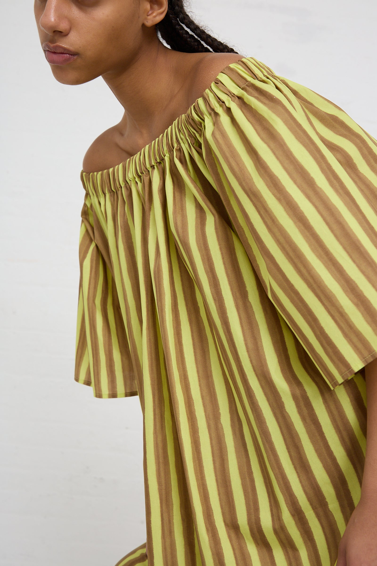 Woman wearing an AVN striped cotton maxi dress with gathered detailing in brown and yellow stripes.