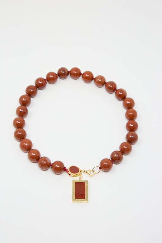 Abby Carnevale 14K Gold Plated Brass Red Jasper Necklace with a rectangular Red Jasper pendant and a small circular accent, featuring 14K gold plated details, arranged on a plain white background.