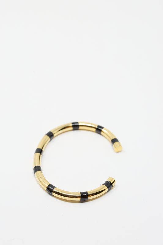 A 14K Gold Plated Brass Striped Cuff in Black by Abby Carnevale is placed on a white background.