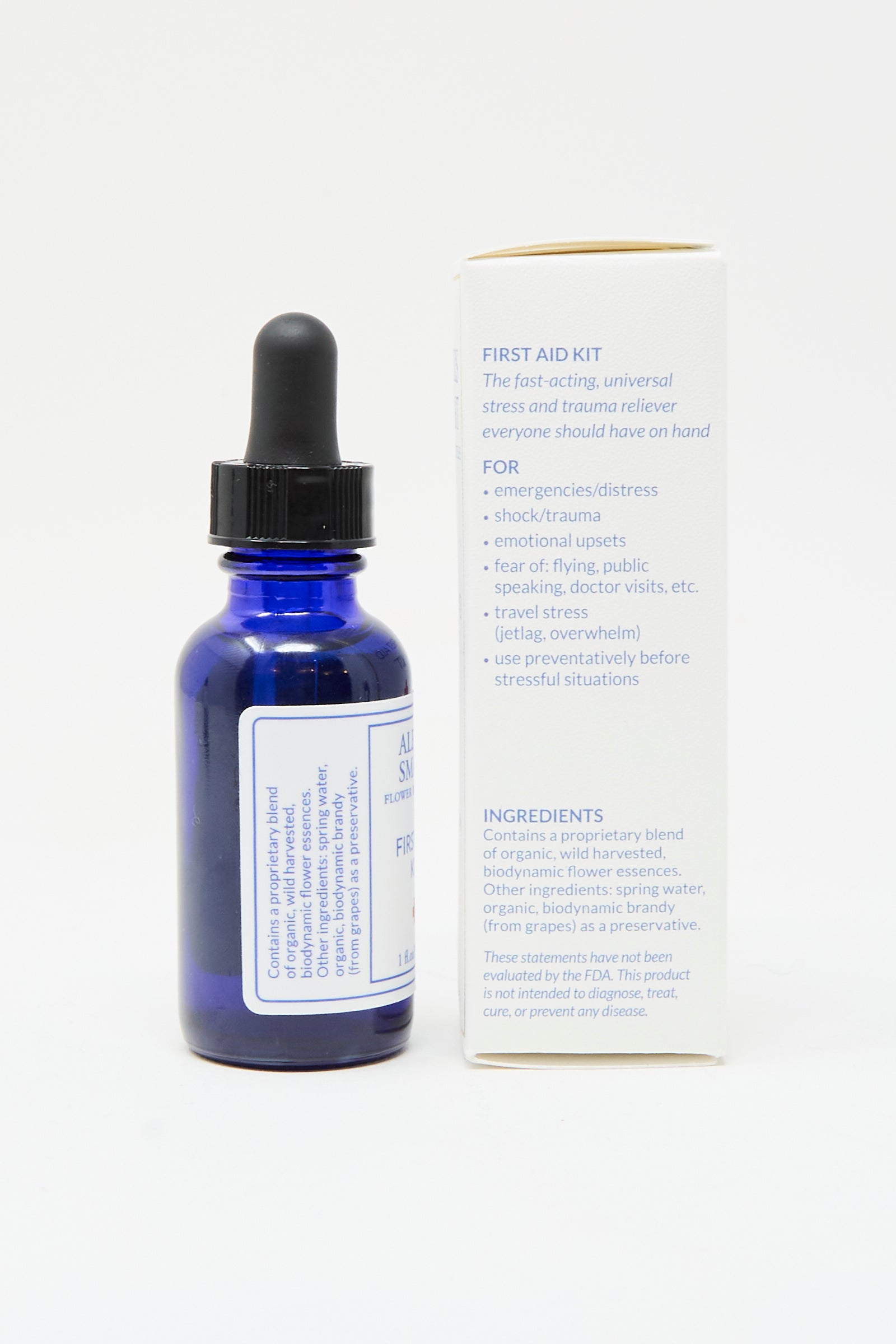 A blue glass dropper bottle labeled "Flower Remedies - First Aid Kit" by Alexis Smart stands beside its box, detailing uses and ingredients—an essential, fast-acting stress relief flower essence for any first aid kit.