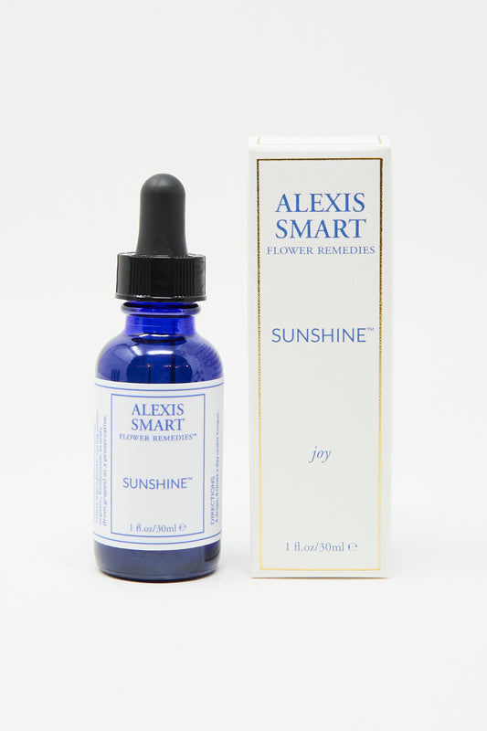 A blue glass dropper bottle labeled "Alexis Smart Flower Remedies - Sunshine" sits next to its white and gold box. This 1 fl. oz./30 ml blend is an organic flower essence designed to support emotional wellness and restore optimism.