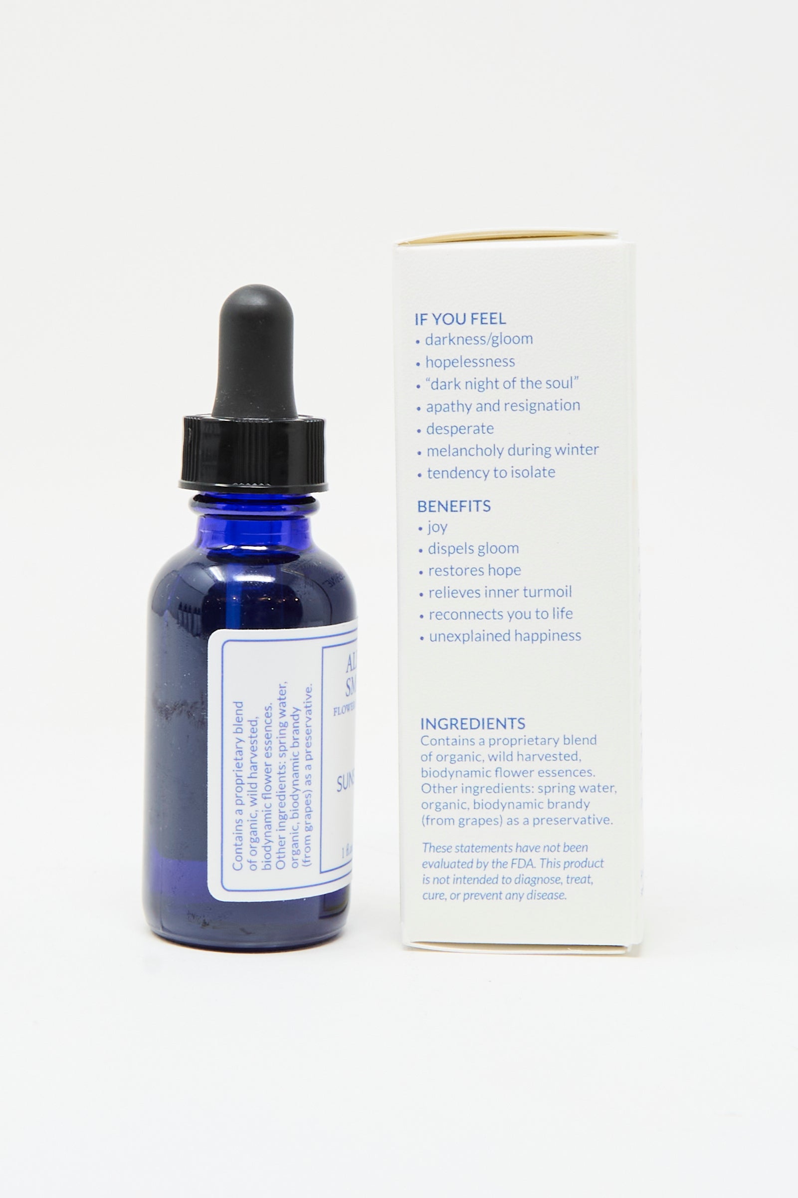 A blue glass dropper bottle of Alexis Smart Flower Remedies - Sunshine stands by its box, which lists uses, benefits, and ingredients for this organic flower essence formula designed to support optimism.