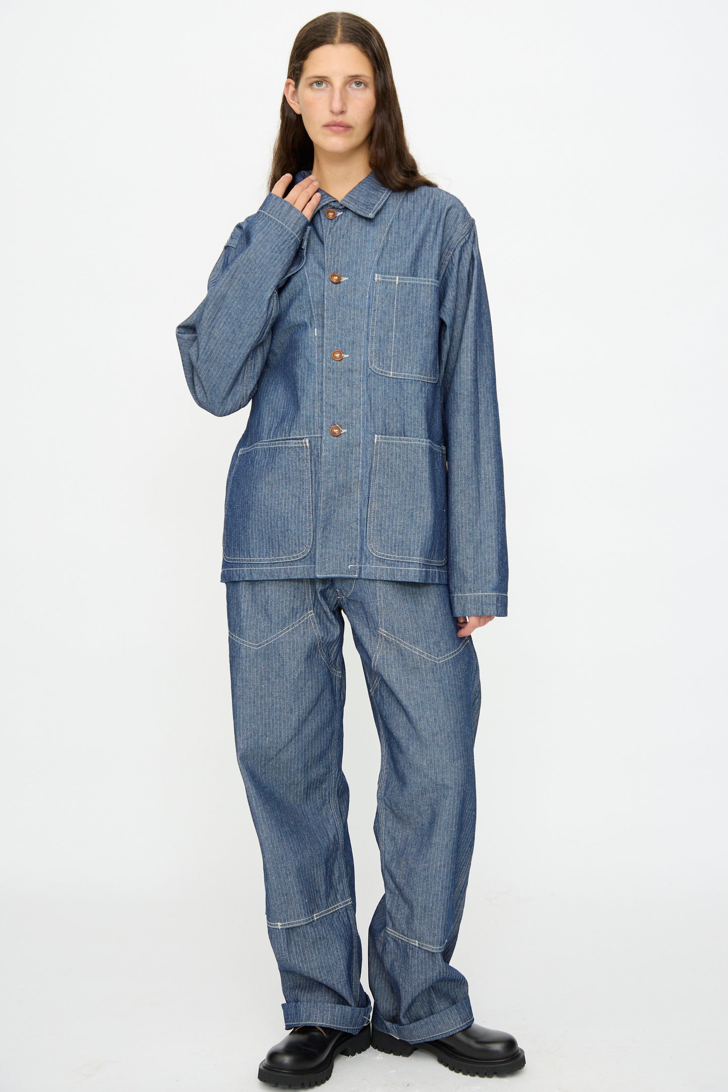 A person stands against a white background, wearing the As Ever Henri Jacket in blue HBT denim with matching pants and black shoes.