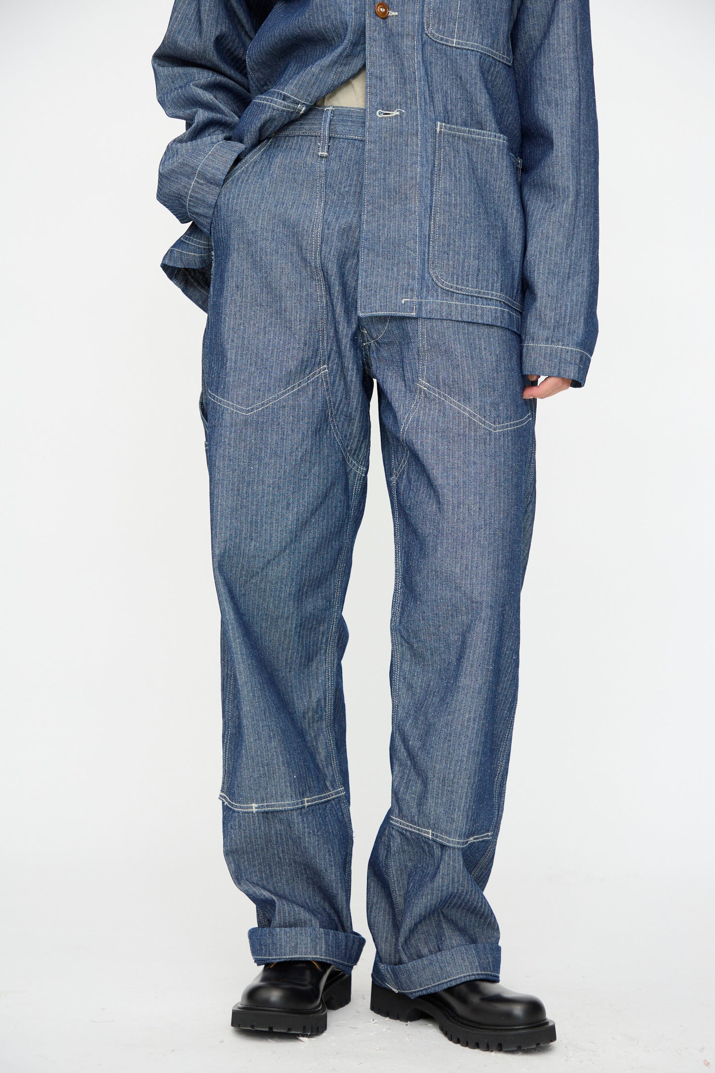 Model wears the Henri Pant in HBT Denim by As Ever, styled with black boots, featuring visible stitching, against a plain white background.