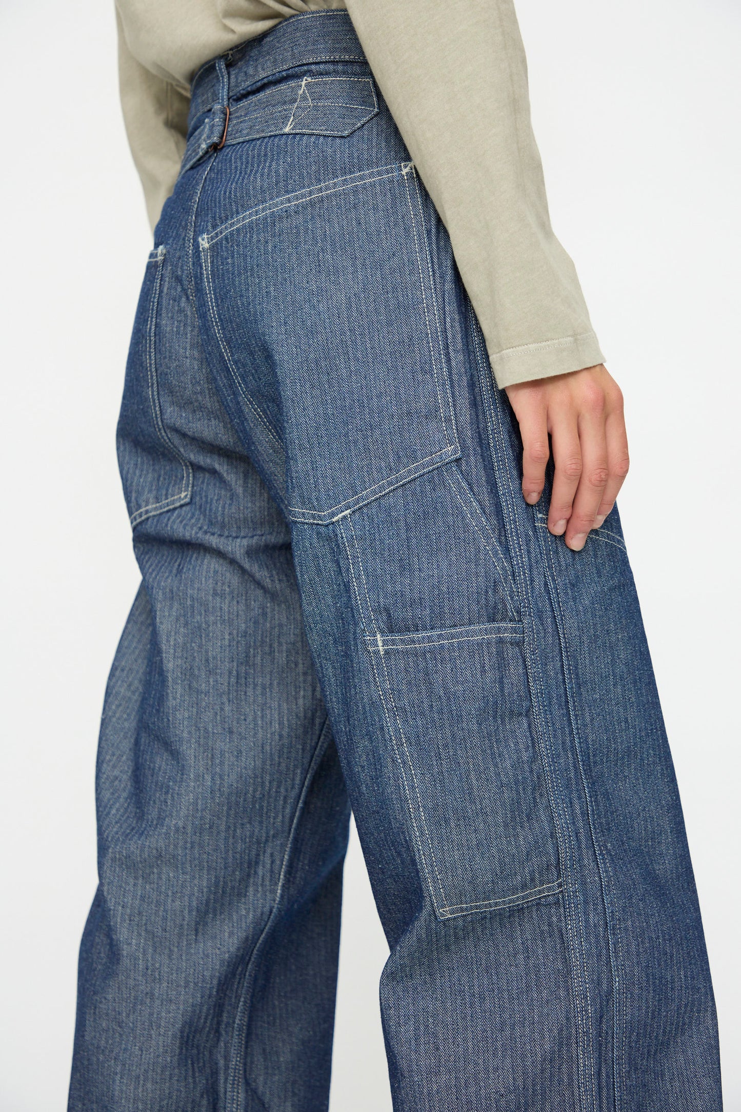 Model wears the As Ever Henri Pant in HBT Denim, featuring oversized blue denim with large pockets, paired with a light-colored long-sleeve shirt; shown waist down from a side view.