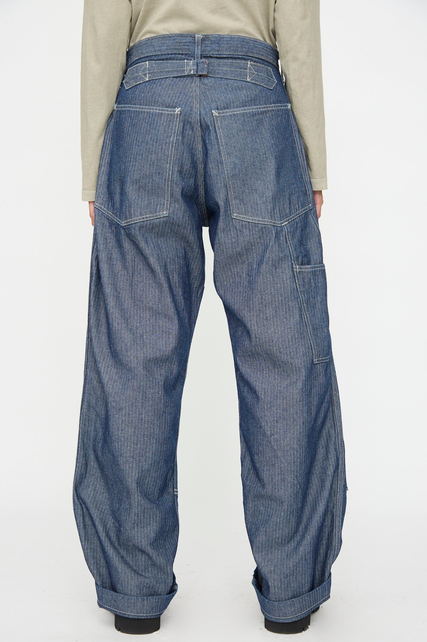 Person wearing As Ever Henri Pant in HBT Denim, featuring a loose fit, high waist, and large back pockets, seen from behind against a plain white background.