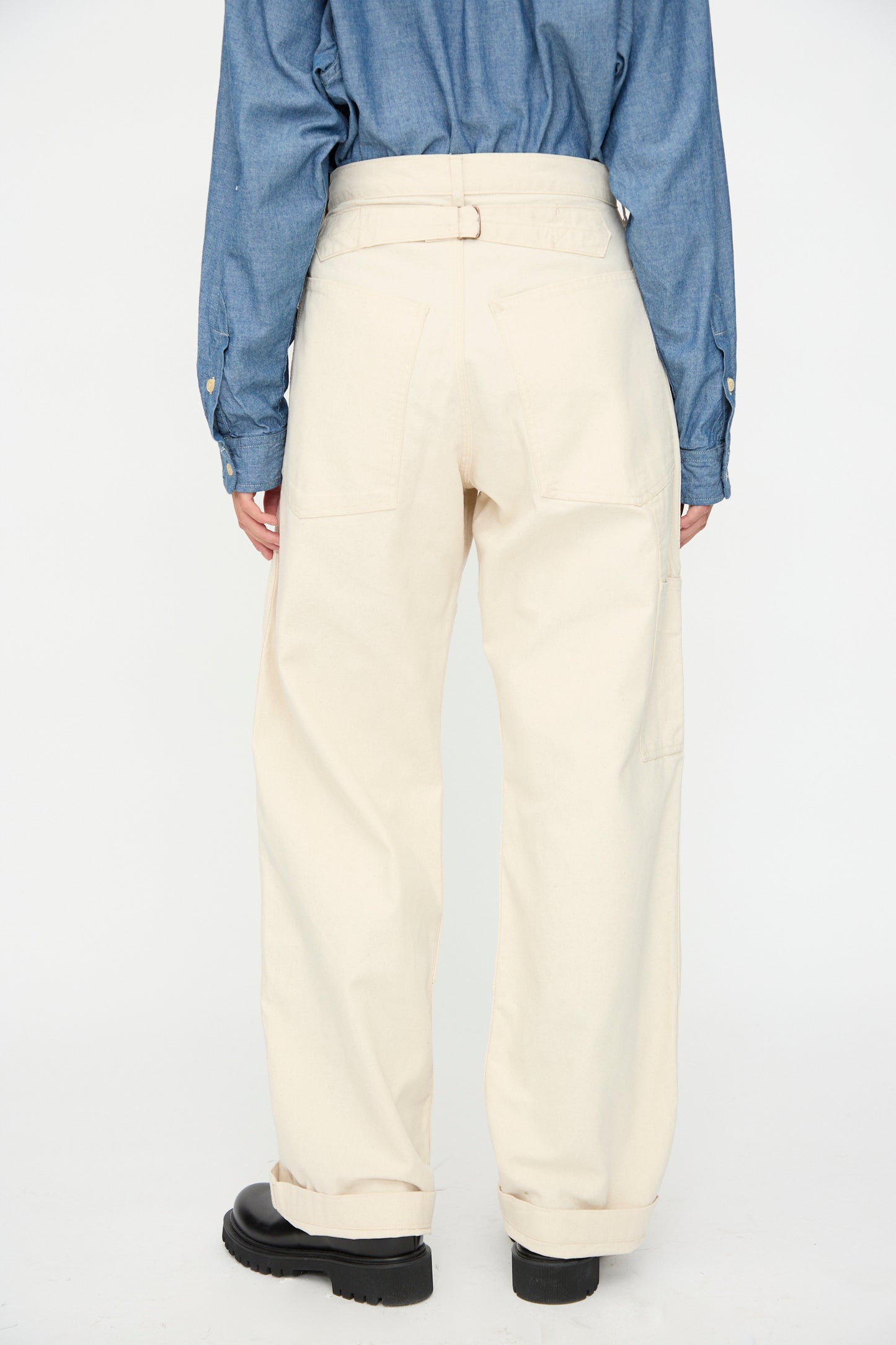 Model shown from the back wearing As Ever's Henri Pant in Natural with a blue button-up shirt and black shoes, set against a plain white background.