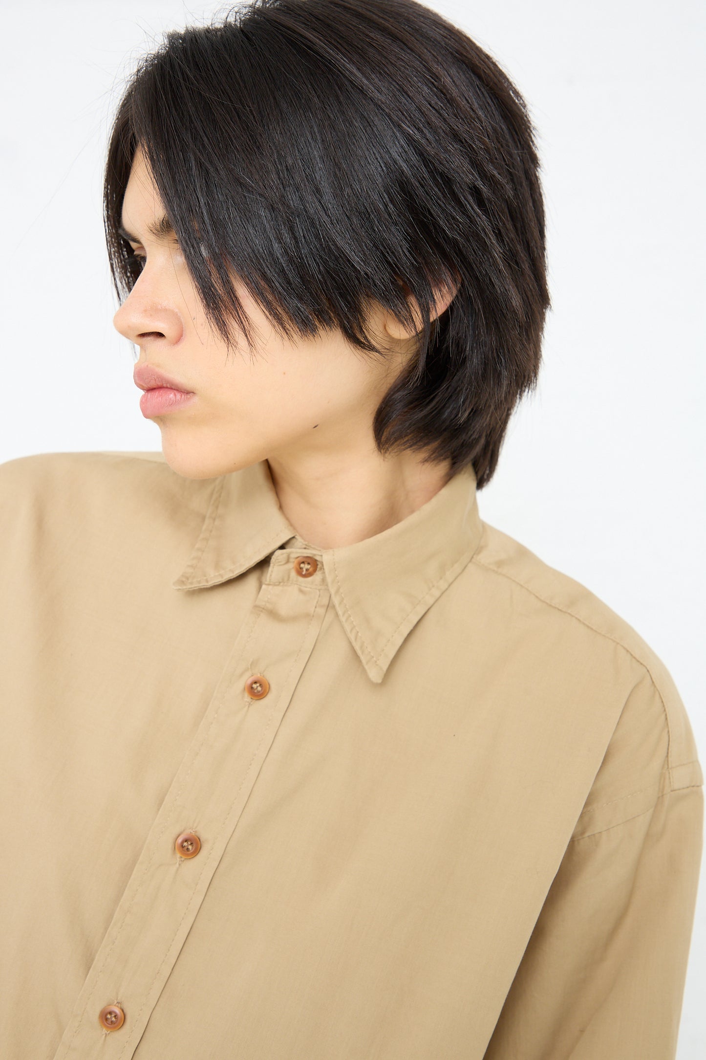 A person with short dark hair and a Largo Shirt in 40's Khaki by As Ever, in a side profile view.