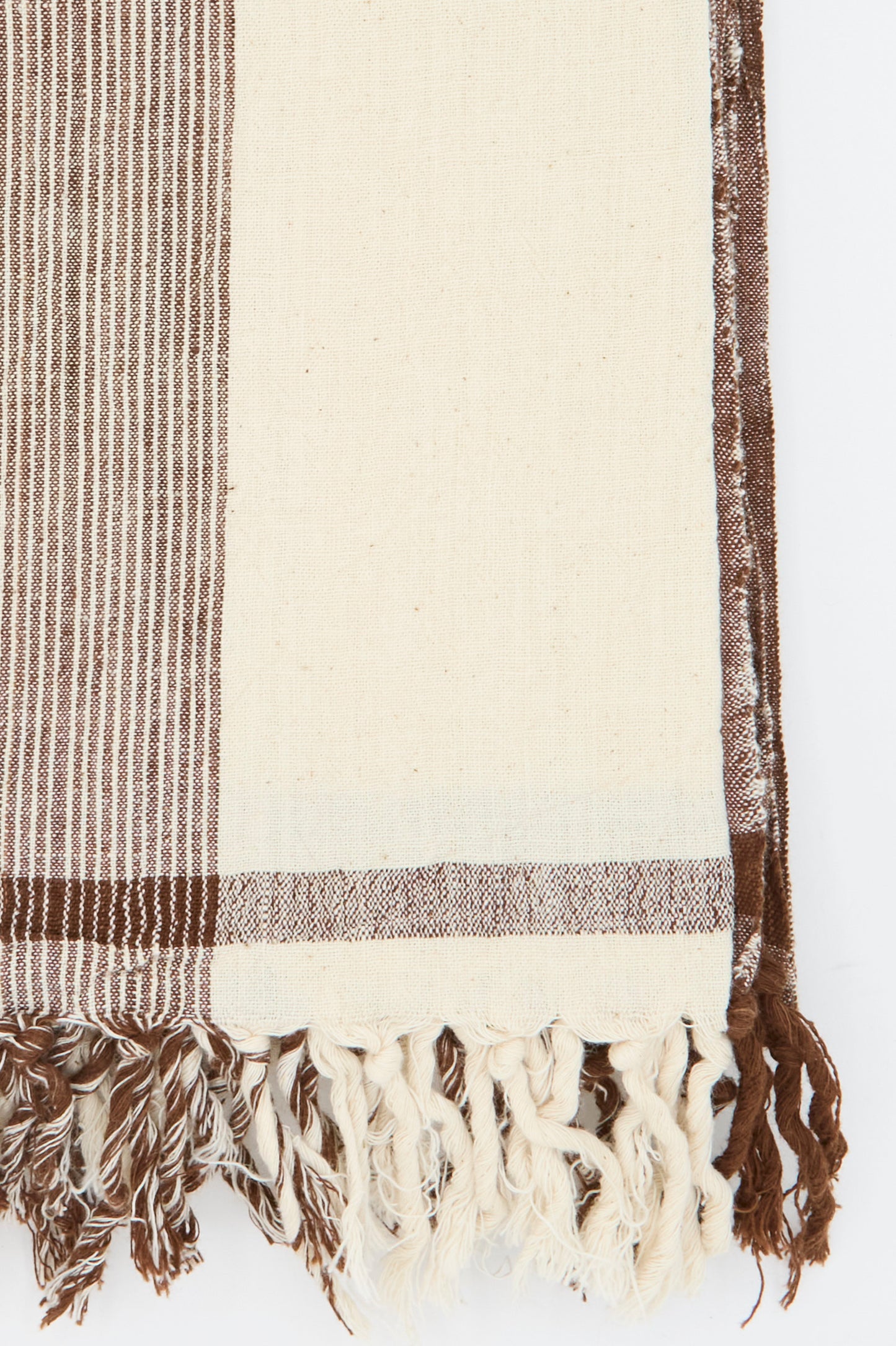 The Auntie Oti Cotton Khadi Natural Dye Towel in Brown Stripe showcases handwoven brown and cream stripes with natural dye variations and fringe along the bottom edge.