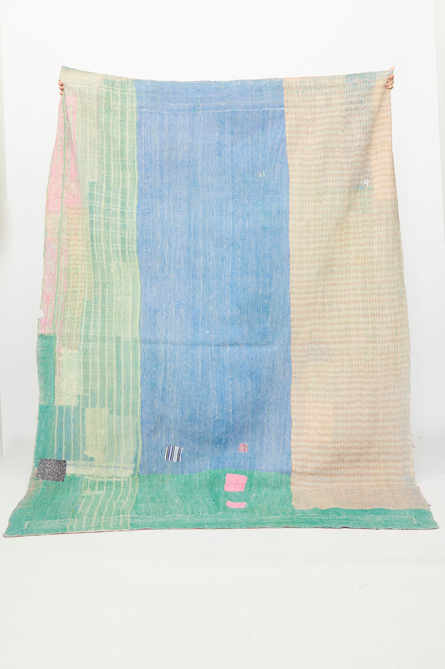 The One of a Kind Vintage Kantha Quilt I by Auntie Oti features vertical sections in light green, blue, and beige with small upcycled cotton patches, shown against a plain white background.