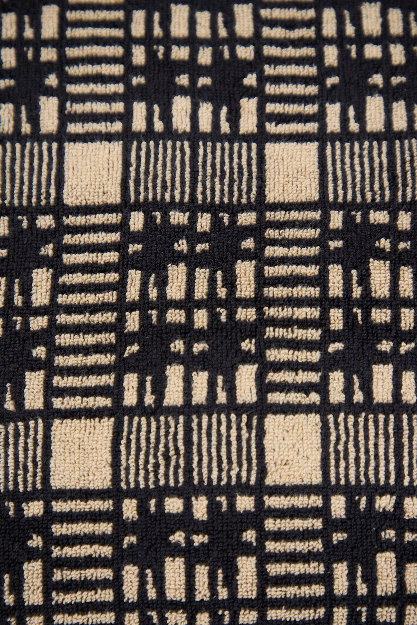 Close-up of the Alma Hand Towel by Autumn Sonata, showcasing its beige and black checkered design with vertical and horizontal lines of varying thickness, crafted from organic cotton.