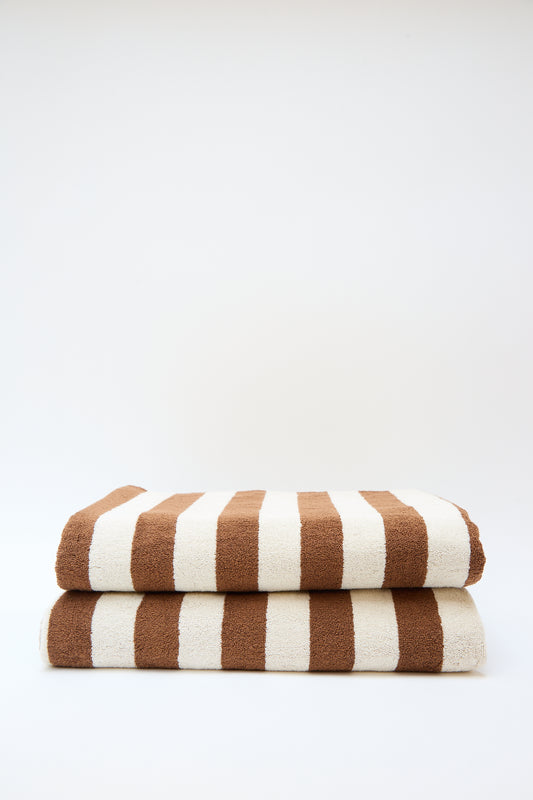Stack of three Autumn Sonata Maria Pool Towels with alternating brown and white stripes against a plain white background.