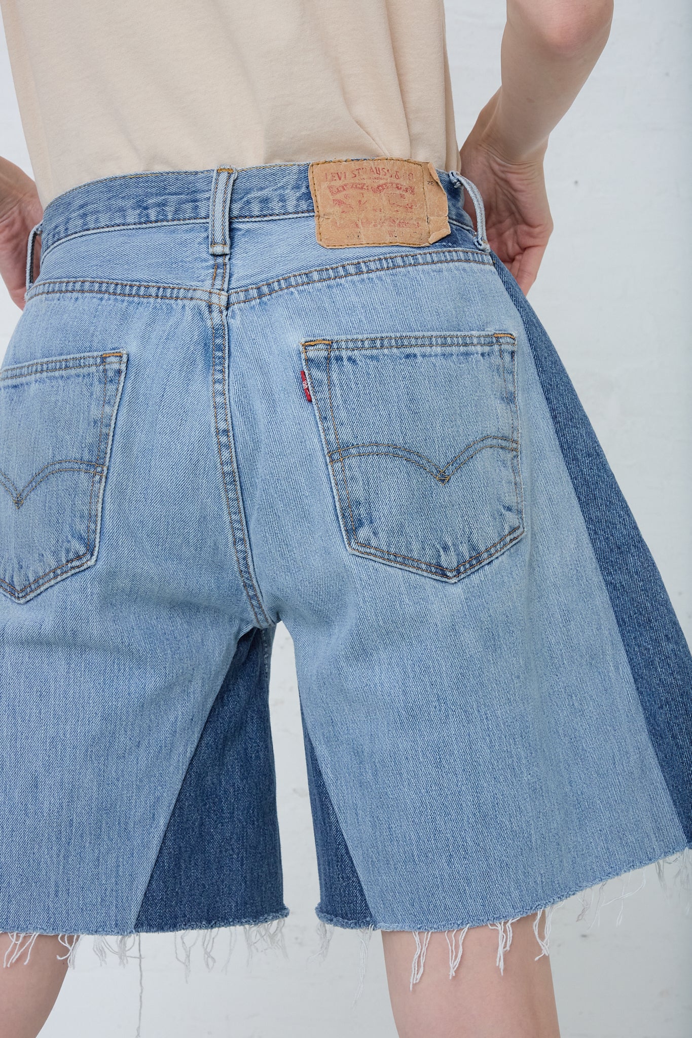 A woman is wearing B Sides Lasso Short in Vintage Indigo denim cutoff shorts. Back view.