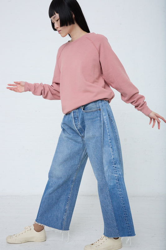 A woman in a B Sides Lasso Jean in Vintage Indigo and pink sweatshirt.
