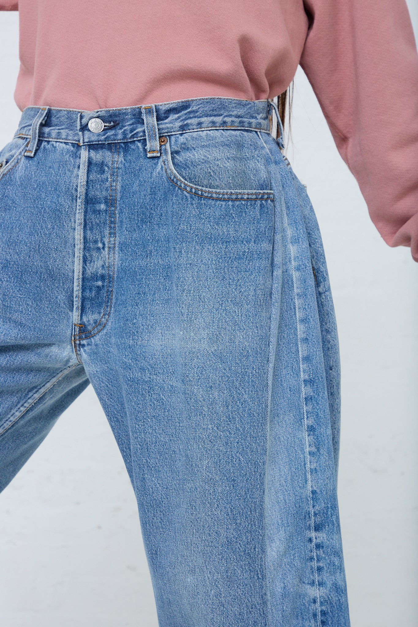 A woman in a pink sweater is wearing B Sides' Lasso Jean in Vintage Indigo.