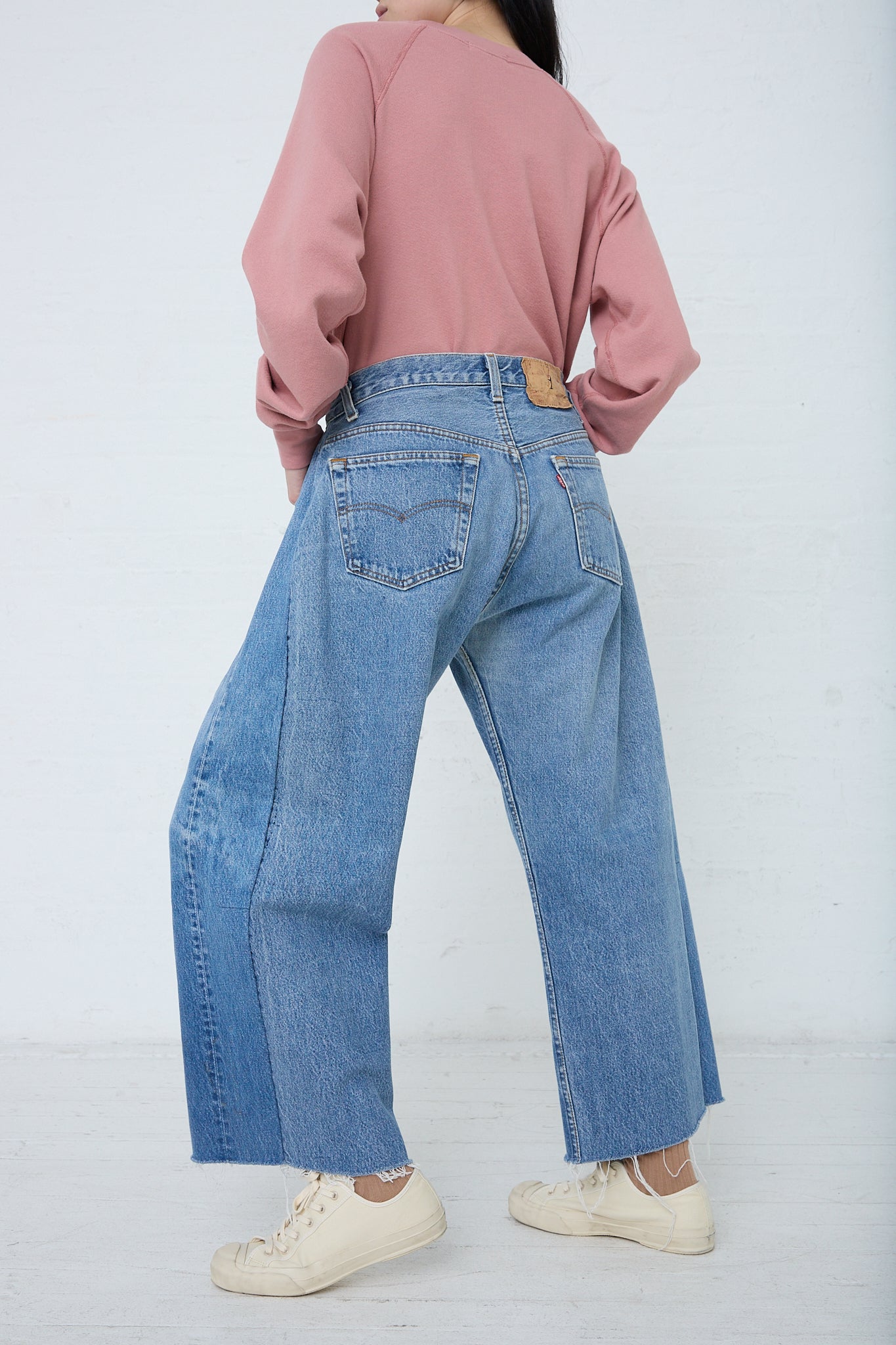 A woman in a pink sweater and B Sides Lasso Jean in Vintage Indigo looks stylish and comfortable. Back view.