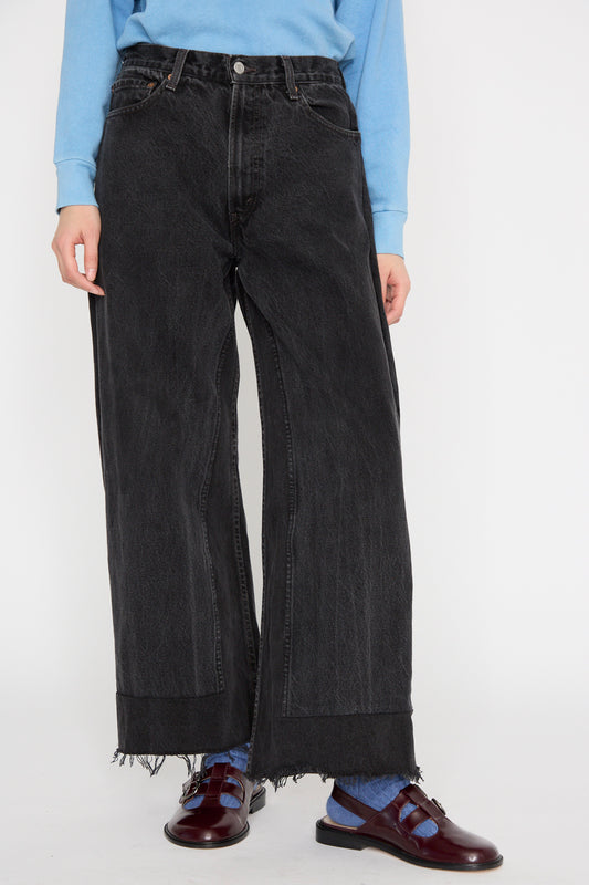 A model wears a blue top and B Sides' Reworked Culotte in Vintage Black, styled as upcycled vintage with frayed hems, seen from below the waist against a white background.