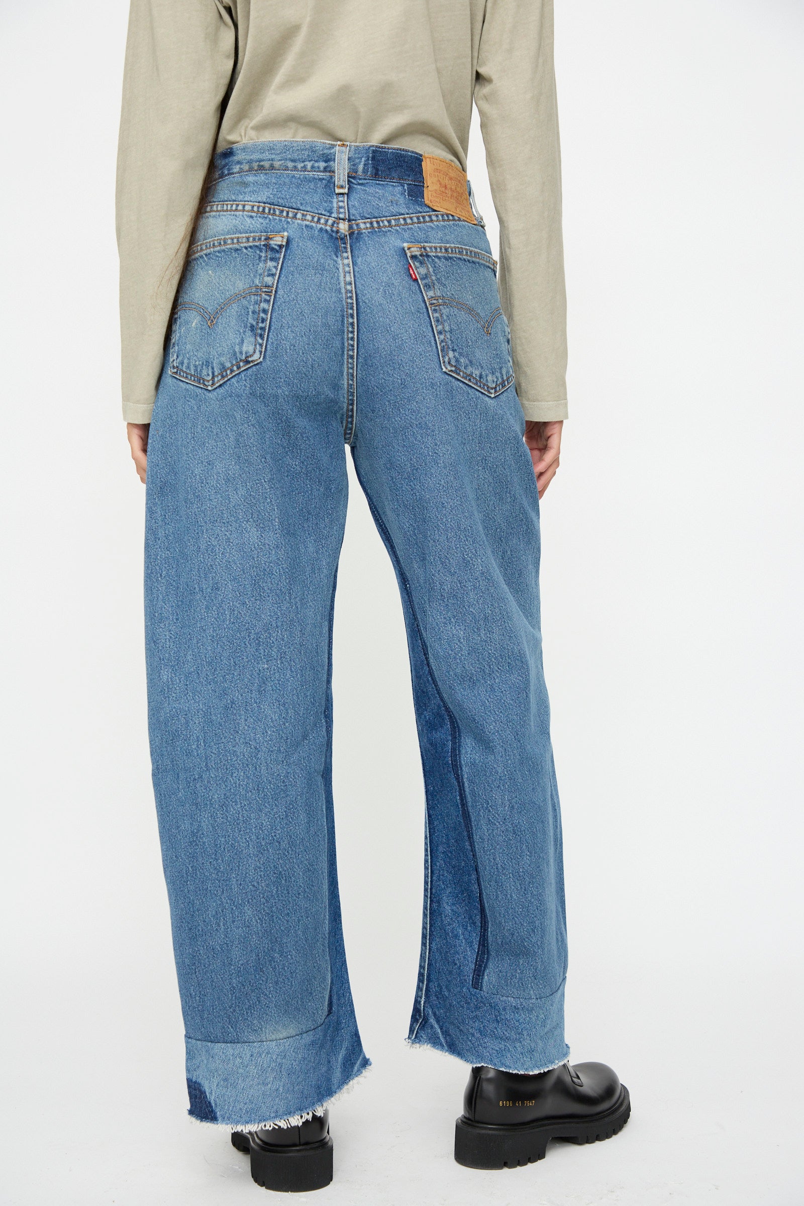 Model seen from the back against a plain white background, wearing B Sides Reworked Culotte in Vintage Indigo, a beige long-sleeve shirt, and black shoes.