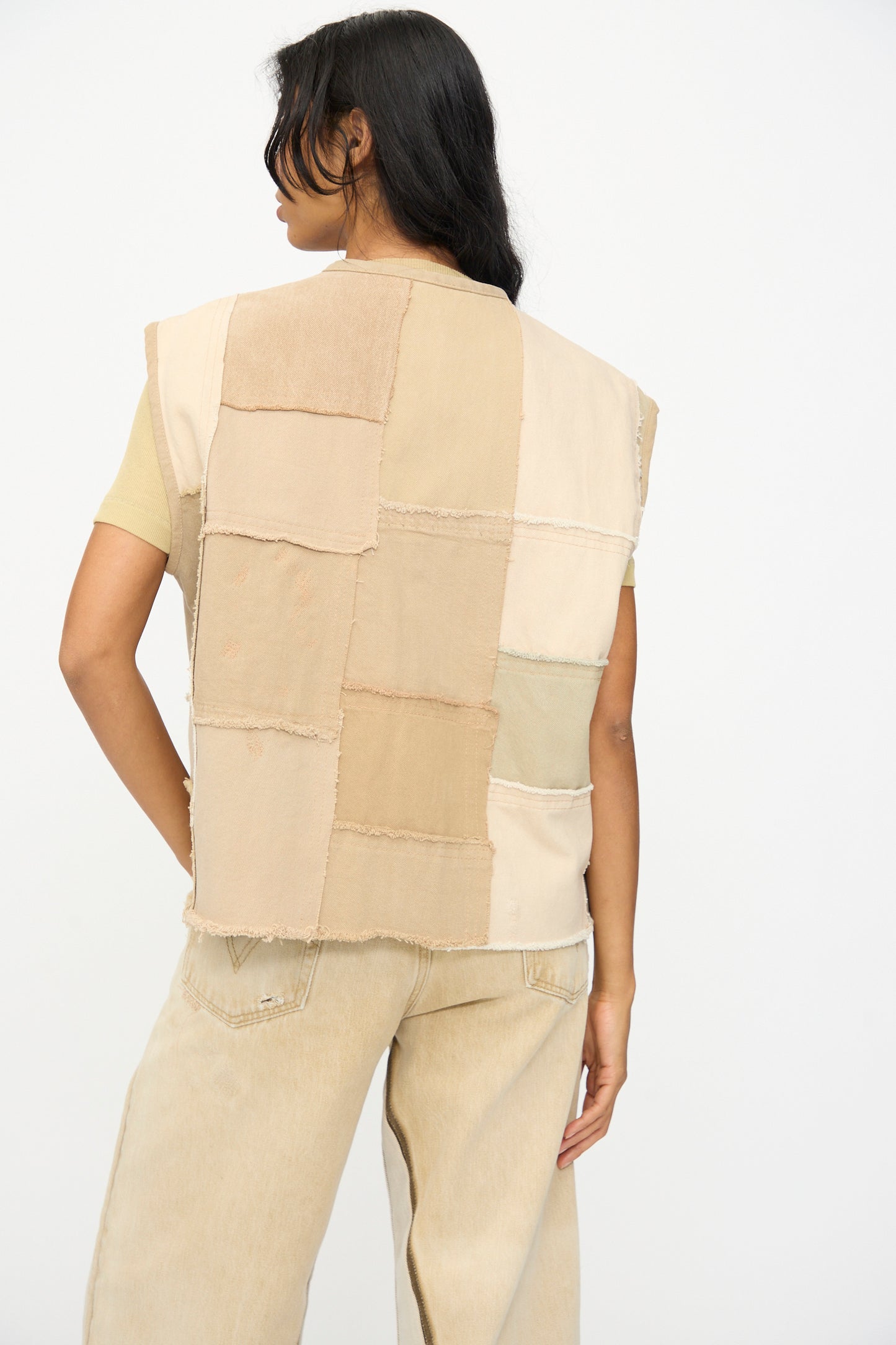A person is shown from the back against a plain white background, wearing the B Sides Vintage Madras Vest in Khaki paired with light-colored pants.