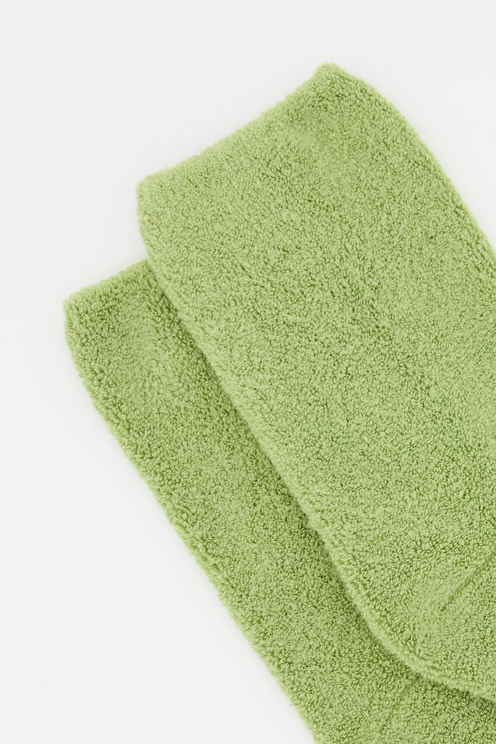 A close-up of two folded Buckle Overankle Socks in Stroma Green by Baserange, made from organic cotton, on a white surface.