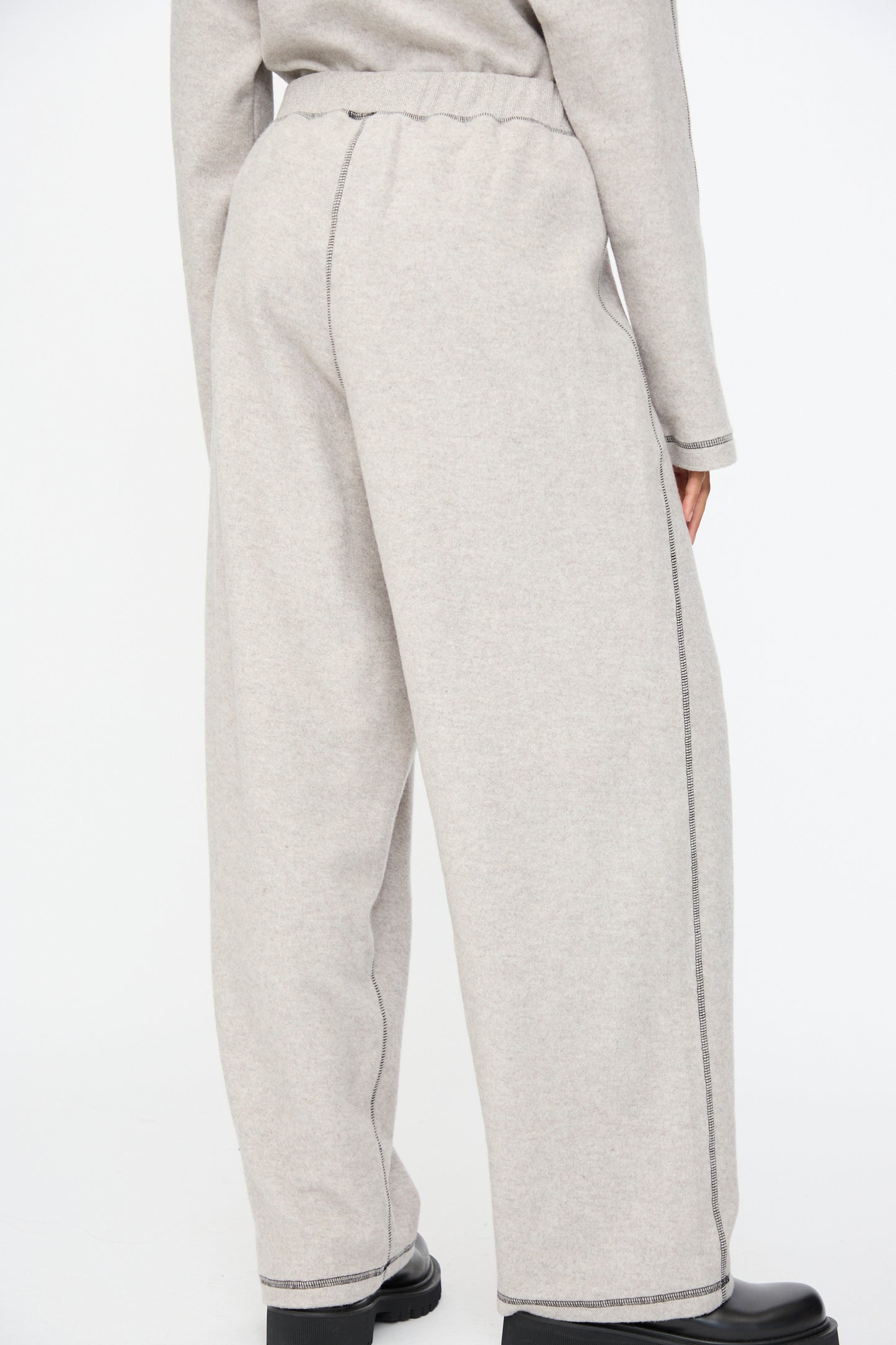 Person wearing Baserange Fold Sweatpant in Grey Melange, a relaxed-fit wide-leg style made from recycled cotton, paired with a matching top and photographed from the back against a plain white background.