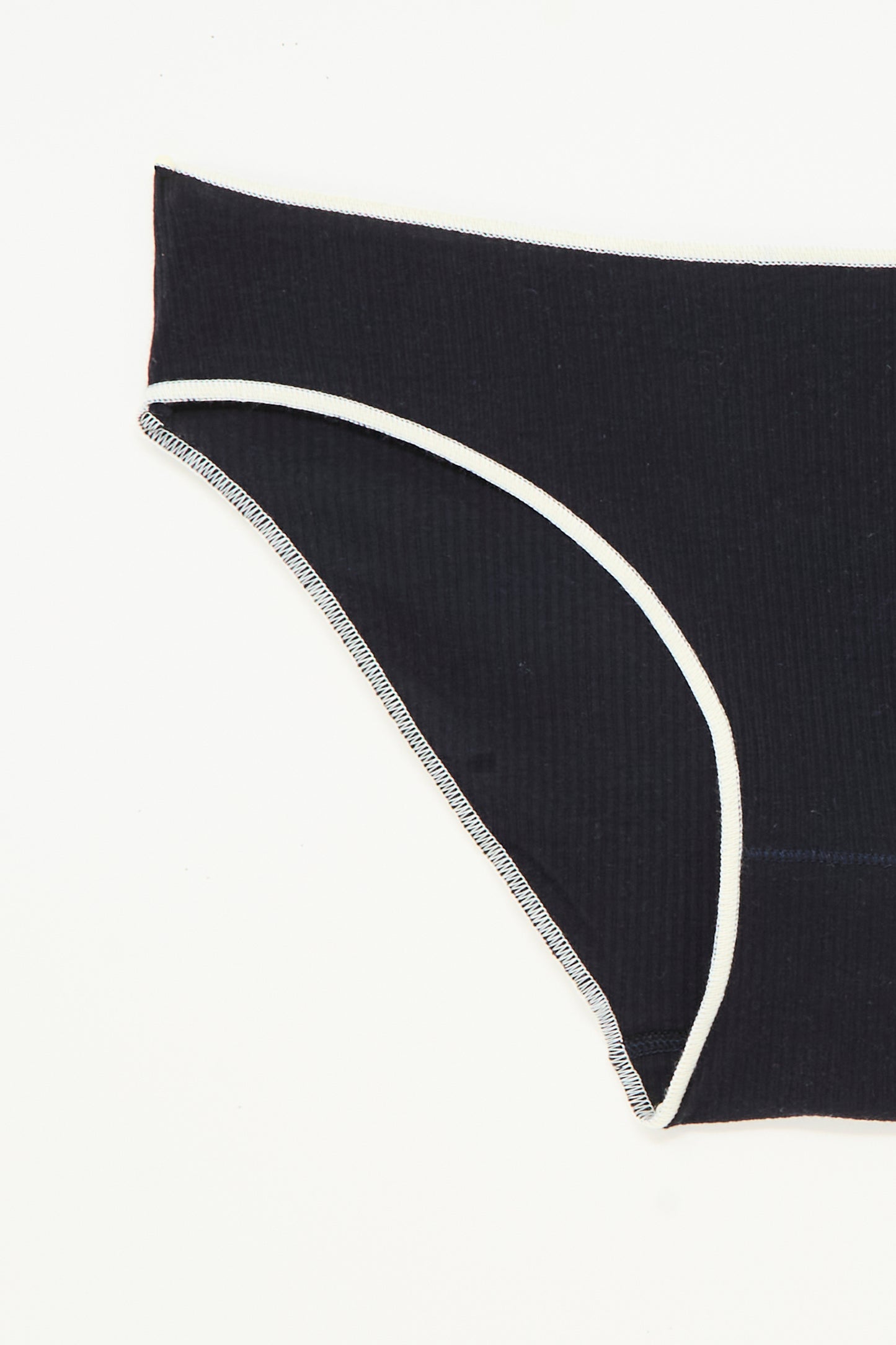 A close-up of the Baserange Pam Pant in Murano Navy, a ribbed organic cotton brief with white trim, laid flat on a white background.