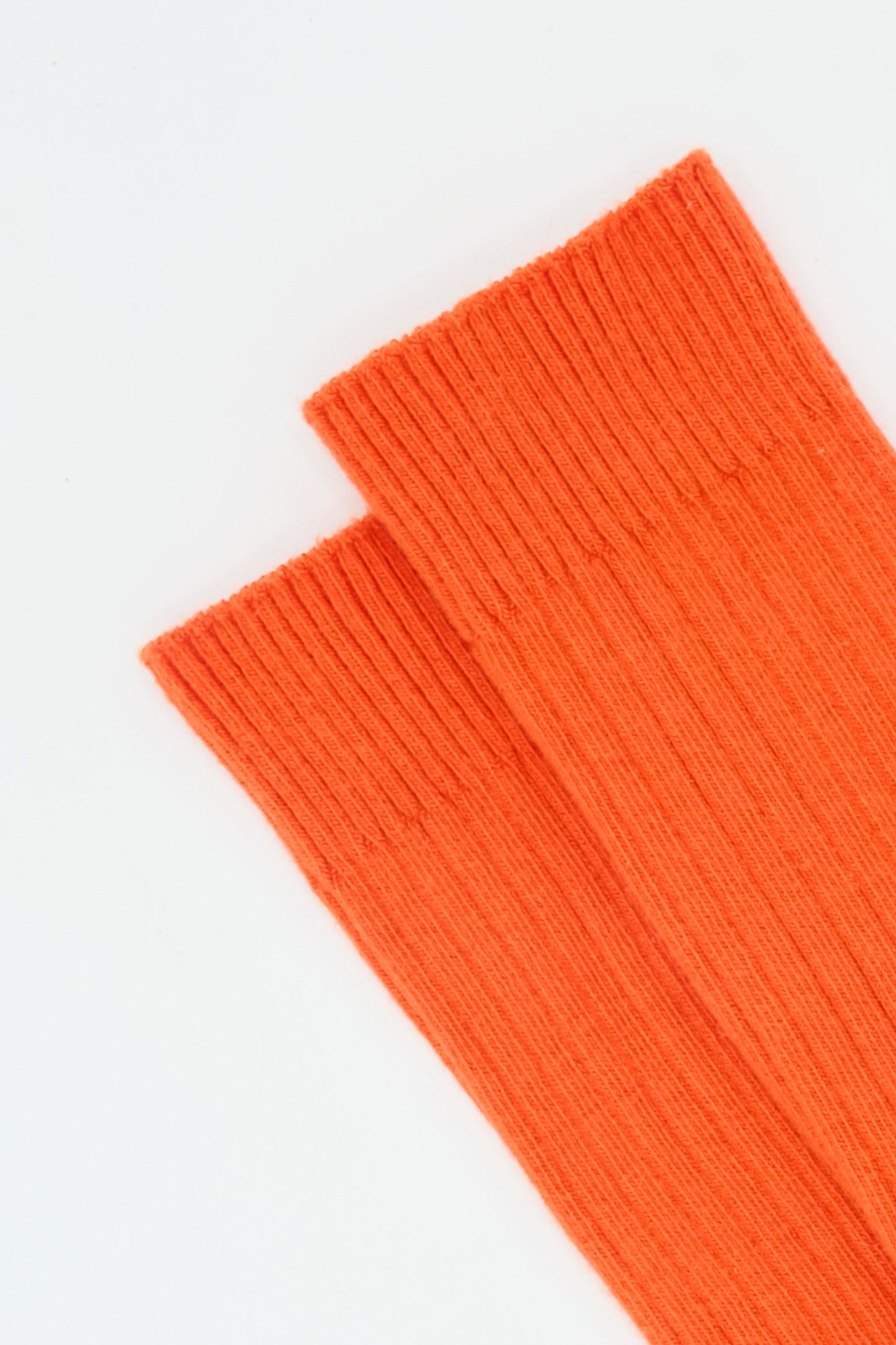 A pair of Baserange Rib Overankle Socks in Chiral Red, ribbed and laid side by side on a white background.