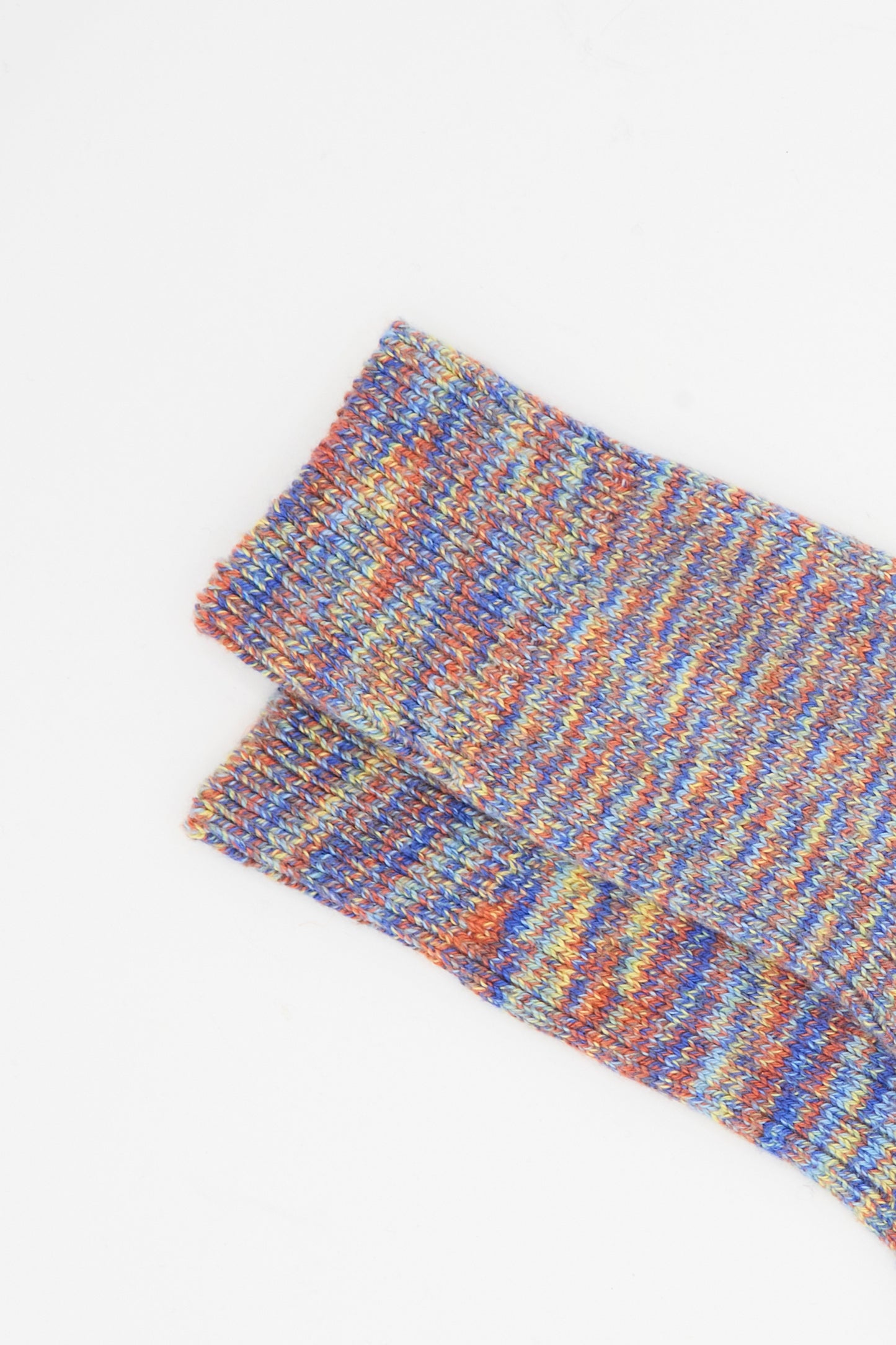 Baserange’s Twist Overankle Socks in Multicolored are stacked on a plain white background. These cotton socks combine style and comfort, making them perfect to brighten up any outfit.