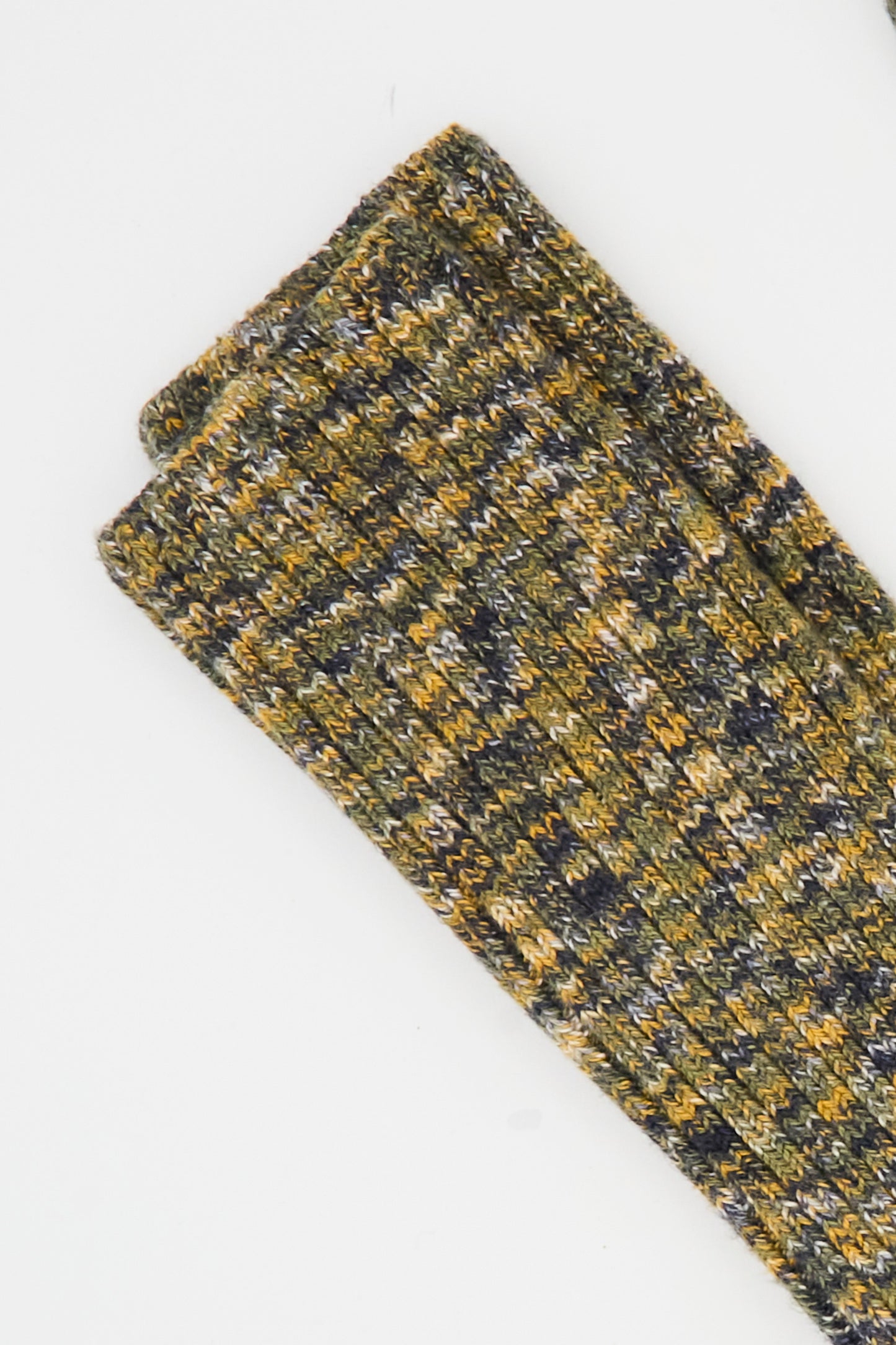 The Baserange Twist Overknee Sock in Olive Green Melange is a rib knit knee-high sock in blended green, yellow, gray, and white tones, folded neatly on a white surface. Made in France.