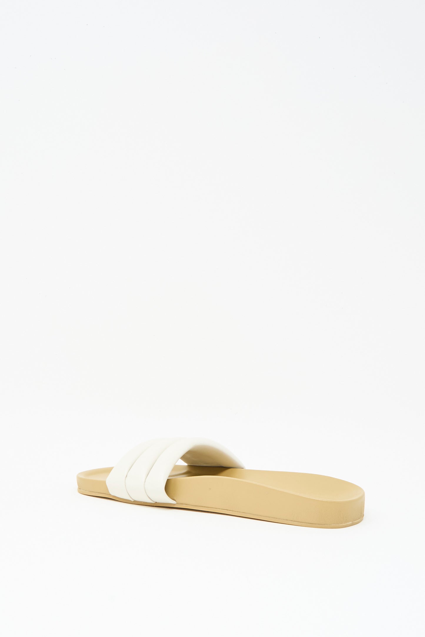 The Classic Sandalia in Shell by Beatrice Valenzuela is a handcrafted beige leather slide sandal featuring a wide white strap, shown against a plain white background.