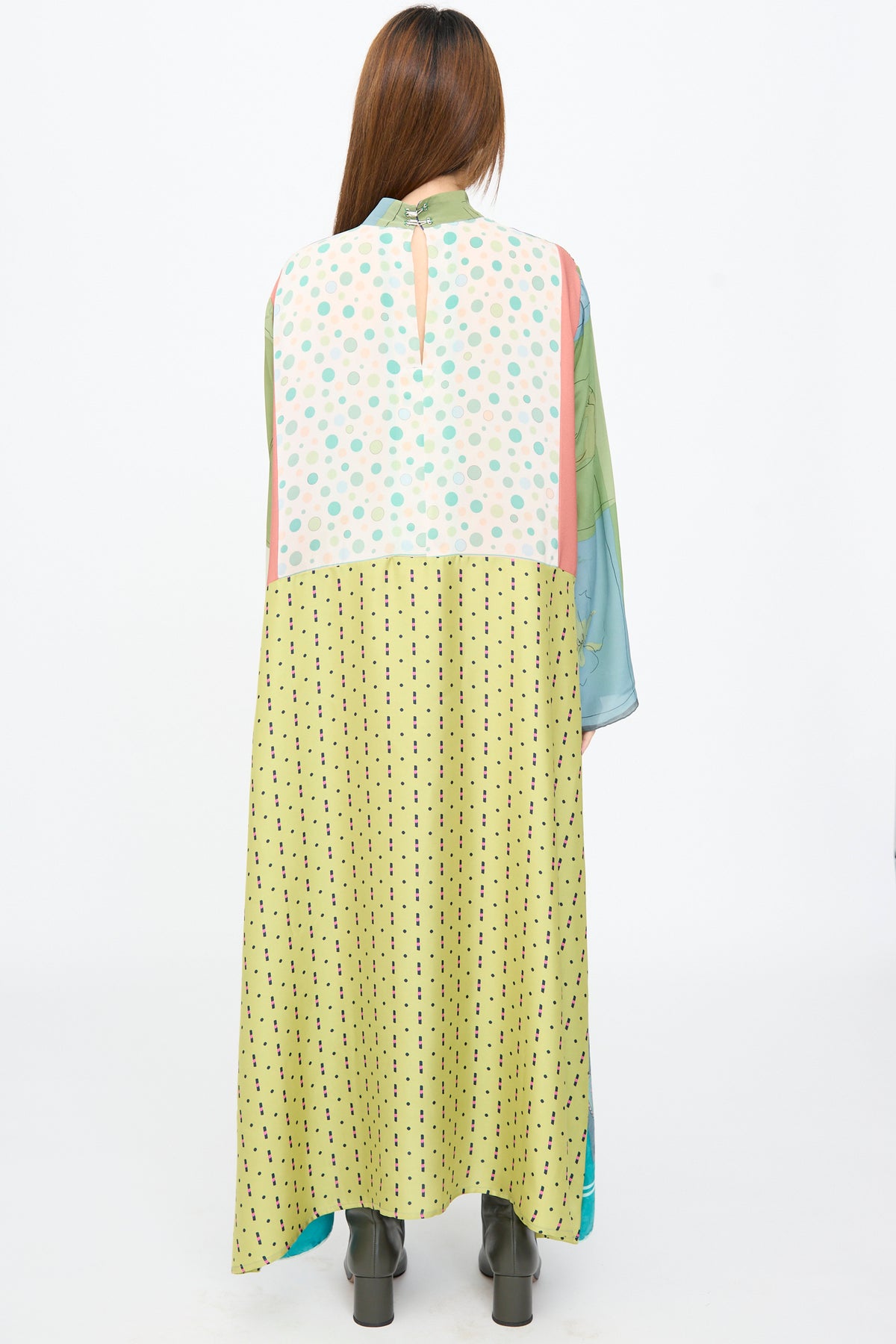 Back view of a person wearing a Bettina Bakdal Classic Mandarin Collar Dress in Hedwig Arheim, a knee-length, up-cycled silk patchwork dress with polka-dot and geometric patterns and grey ankle boots.