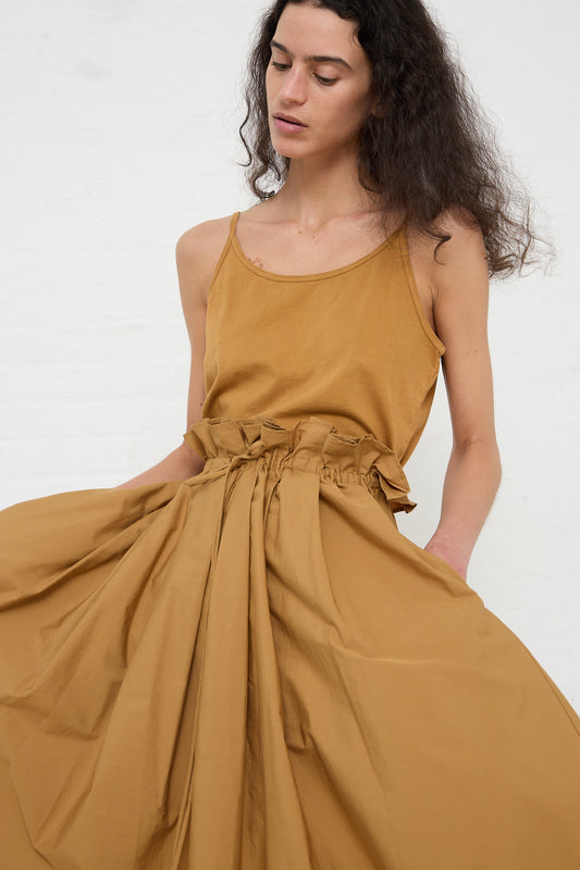 Woman wearing a Black Crane mustard-colored Cotton Jersey Camisole in Camel dress with a gathered waist detail, crafted from organic cotton.