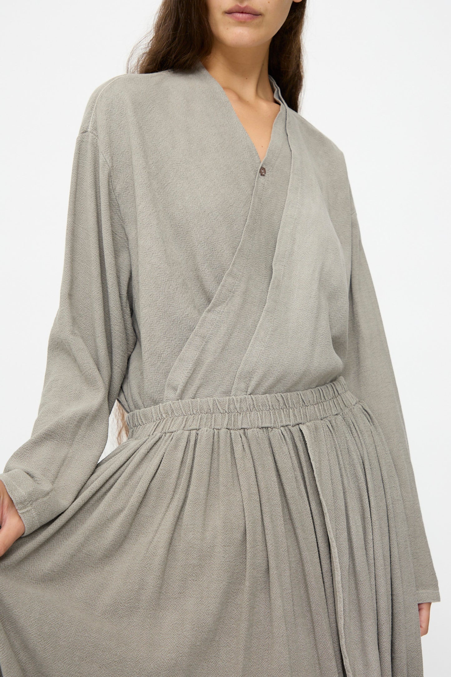 A person wearing the Black Crane Double Layered Drapy Skirt in Dark Stone stands against a plain white background.