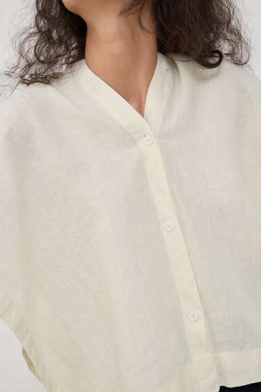 Close-up of a person wearing a White Linen Origami Top in Cream by Black Crane, with visible buttons and a collar, featuring a boxy fit.