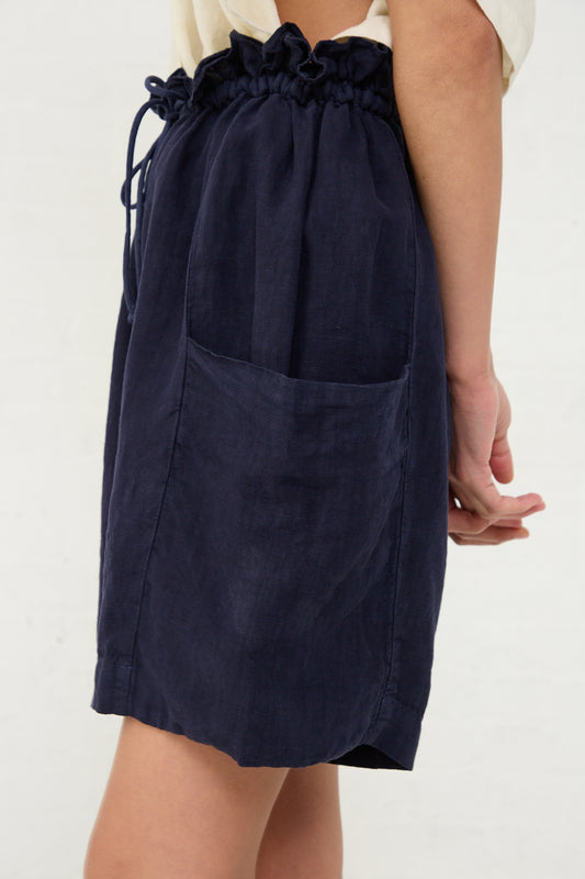 A side view of a person wearing Black Crane's Linen Parachute Short in Indigo with a single visible pocket, against a neutral background, paired with Black Crane linen parachute shorts.