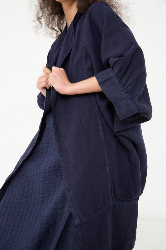 Woman in a textured Linen Spoon Jacket in Indigo by Black Crane holding the garment with her left hand.