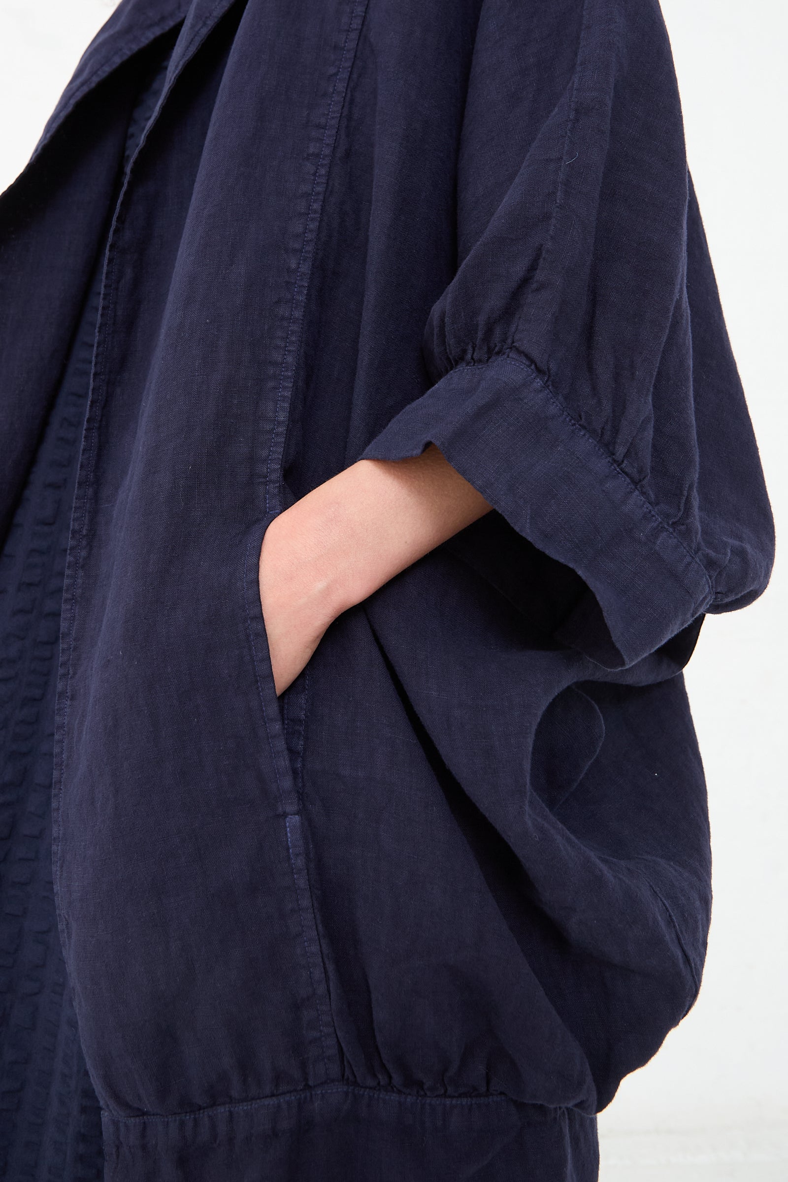 A person in a Linen Spoon Jacket in Indigo from Black Crane with a hand casually placed in a pocket.