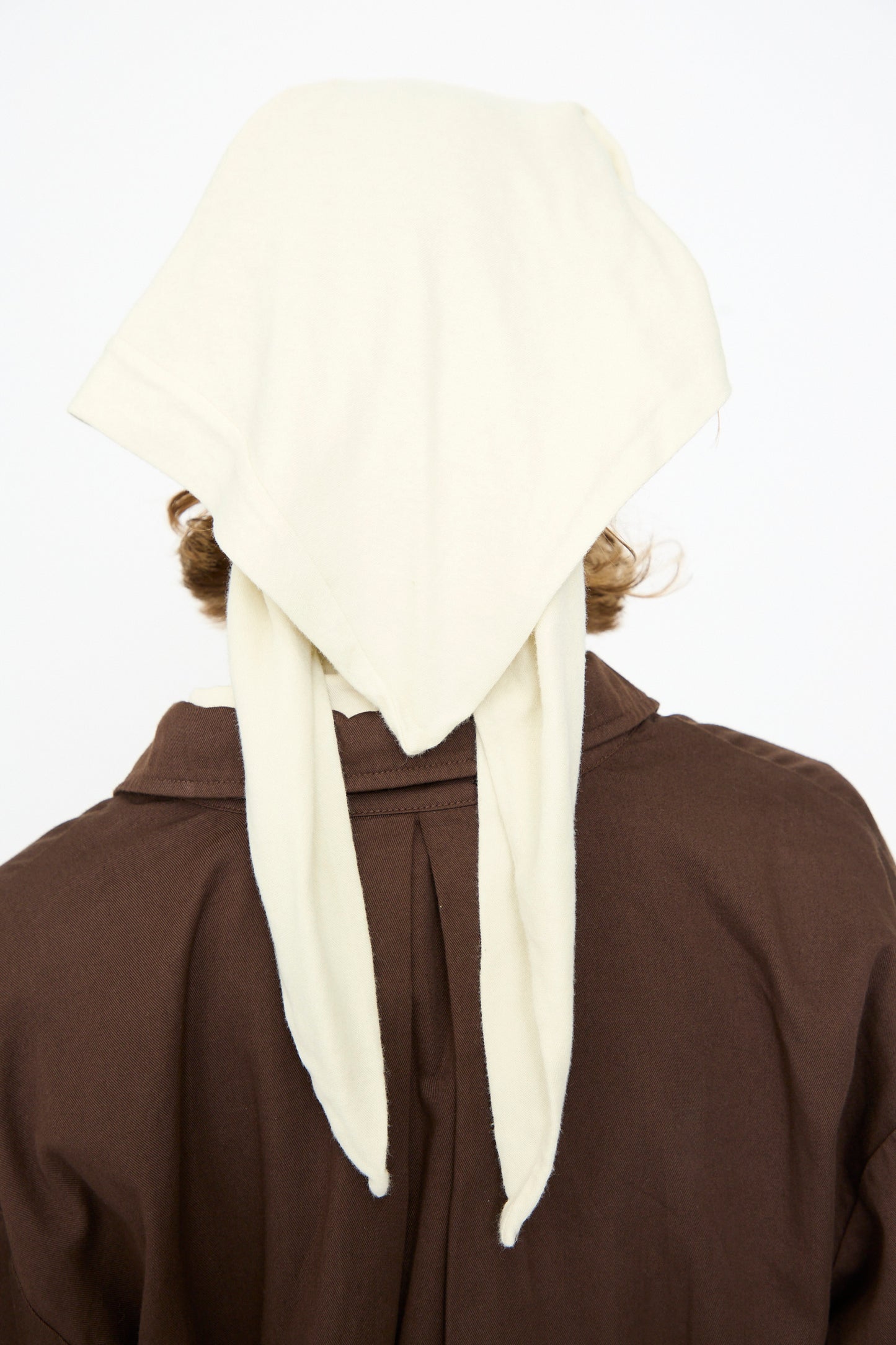 A person, shown from behind against a plain white background, wears a brown garment paired with the Black Crane Triangle Scarf in Natural, tied at the back.
