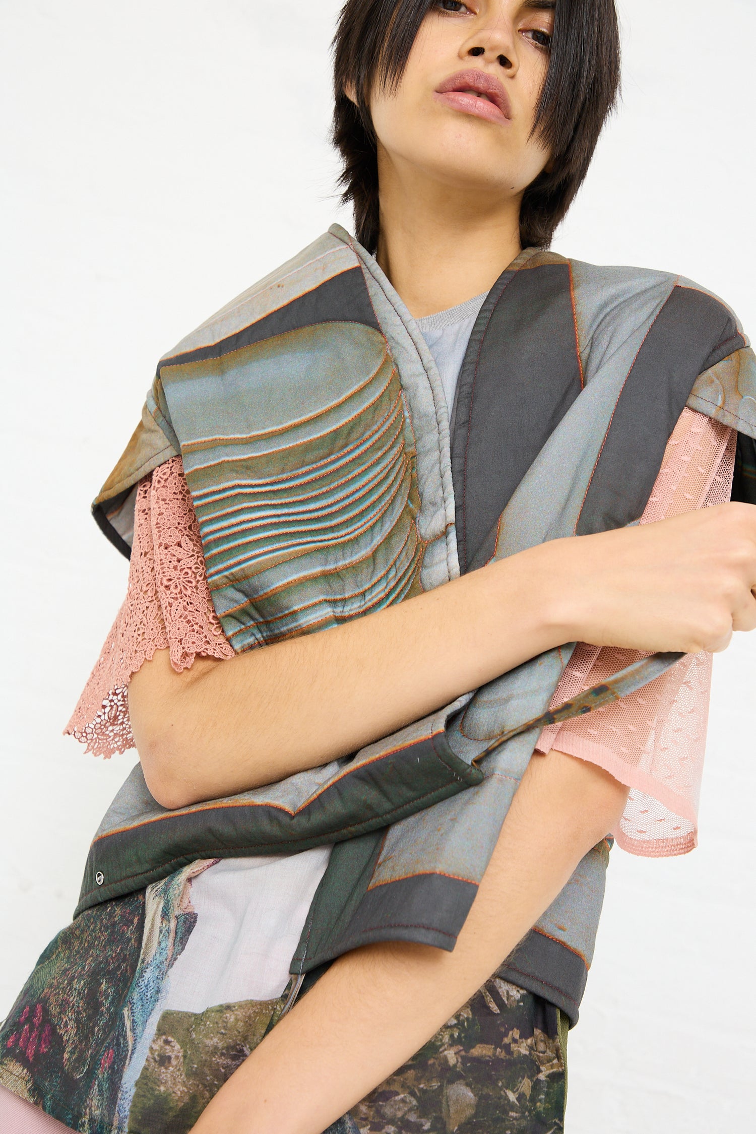 A person in a layered outfit featuring a Bless Cotton No. 77 Summer Living Vest in Print with textured fabrics against a white background.