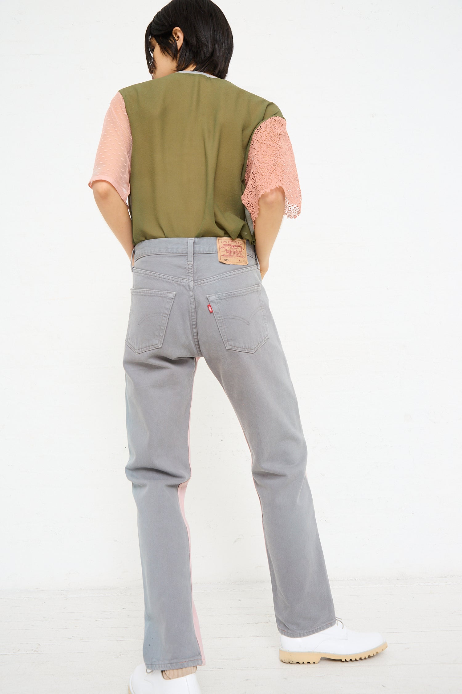 Woman from behind wearing Bless No. 73 Jeanspleatfront in Pink/Grey and a two-toned shirt with a pink sleeve detail.