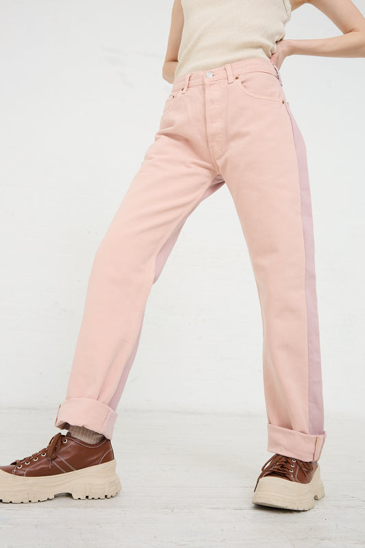 Person wearing Bless No. 73 Jeanspleatfront in Pink/Purple denim trousers with a side stripe and chunky brown shoes.