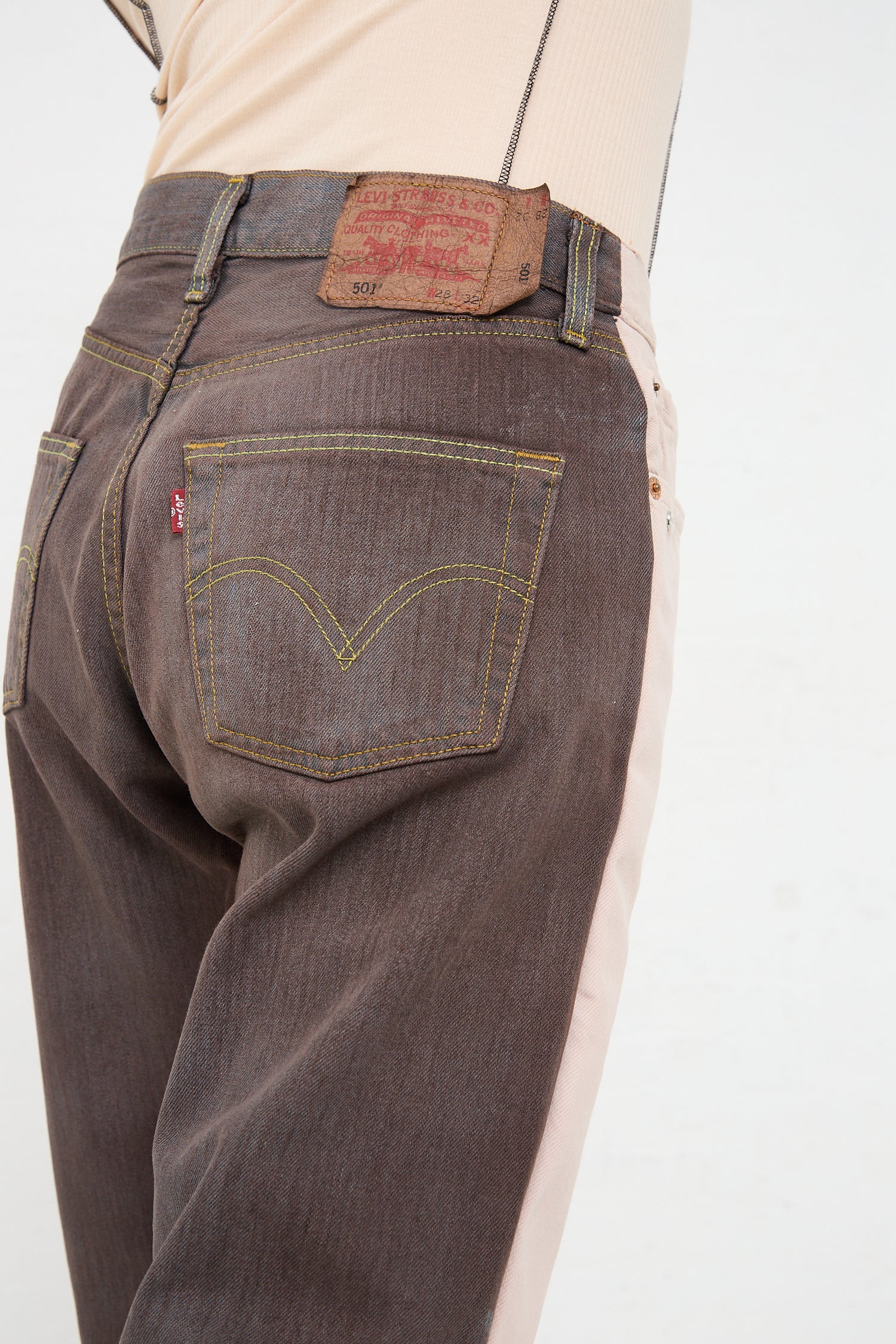 Close-up of a person wearing Bless's No. 73 Jeanspleatfront in Pink/Brown with a visible leather patch label on the waistband from the luxury lifestyle brand.
